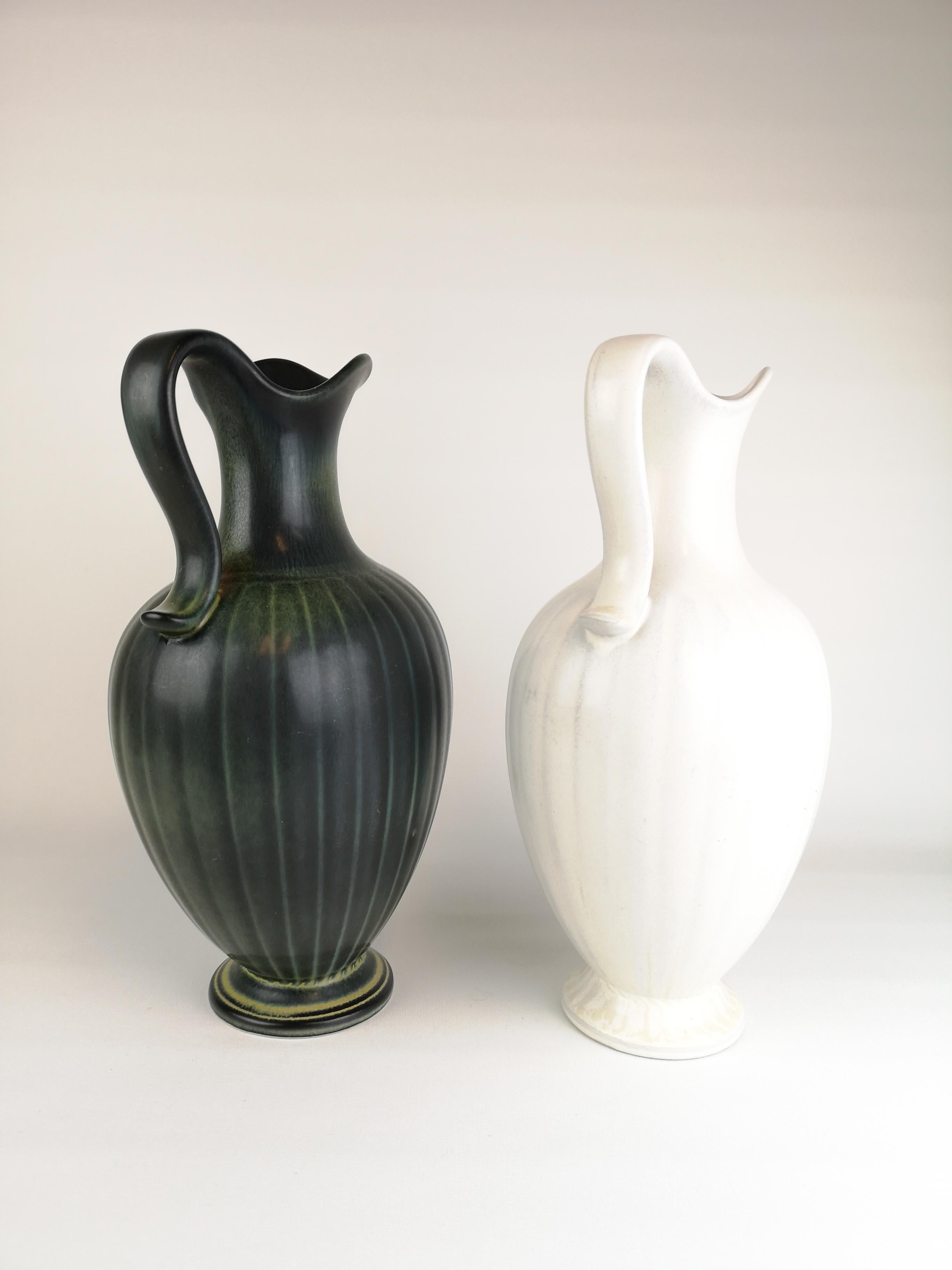 Two wonderful vases from Rörstrand and maker/Designer Gunnar Nylund. Made in Sweden in the midcentury. Beautiful glazed vases in good condition. 

The dark green has a mark on foot. And the white has a glaze mistake on the top. 

 