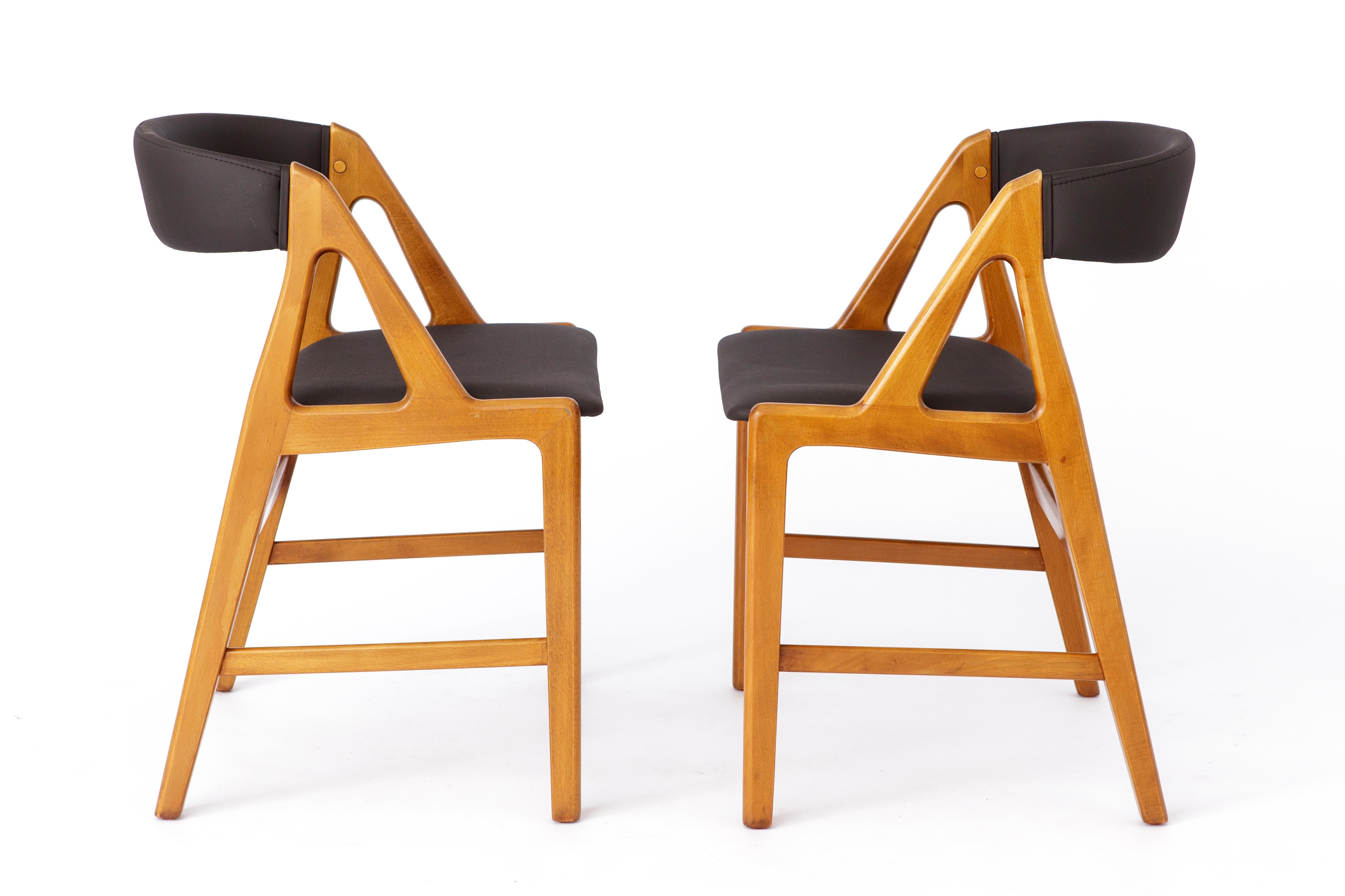 2 chaises de salle à manger vintage des années 1960. 
Conçu par le designer de meubles danois Henning Kjaernulf. 
Modèle : 72. 
Le prix affiché est pour 2 chaises. 

Très bon état. Cadres en hêtre teinté stable. 
Rembourrage en skaï noir (cuir