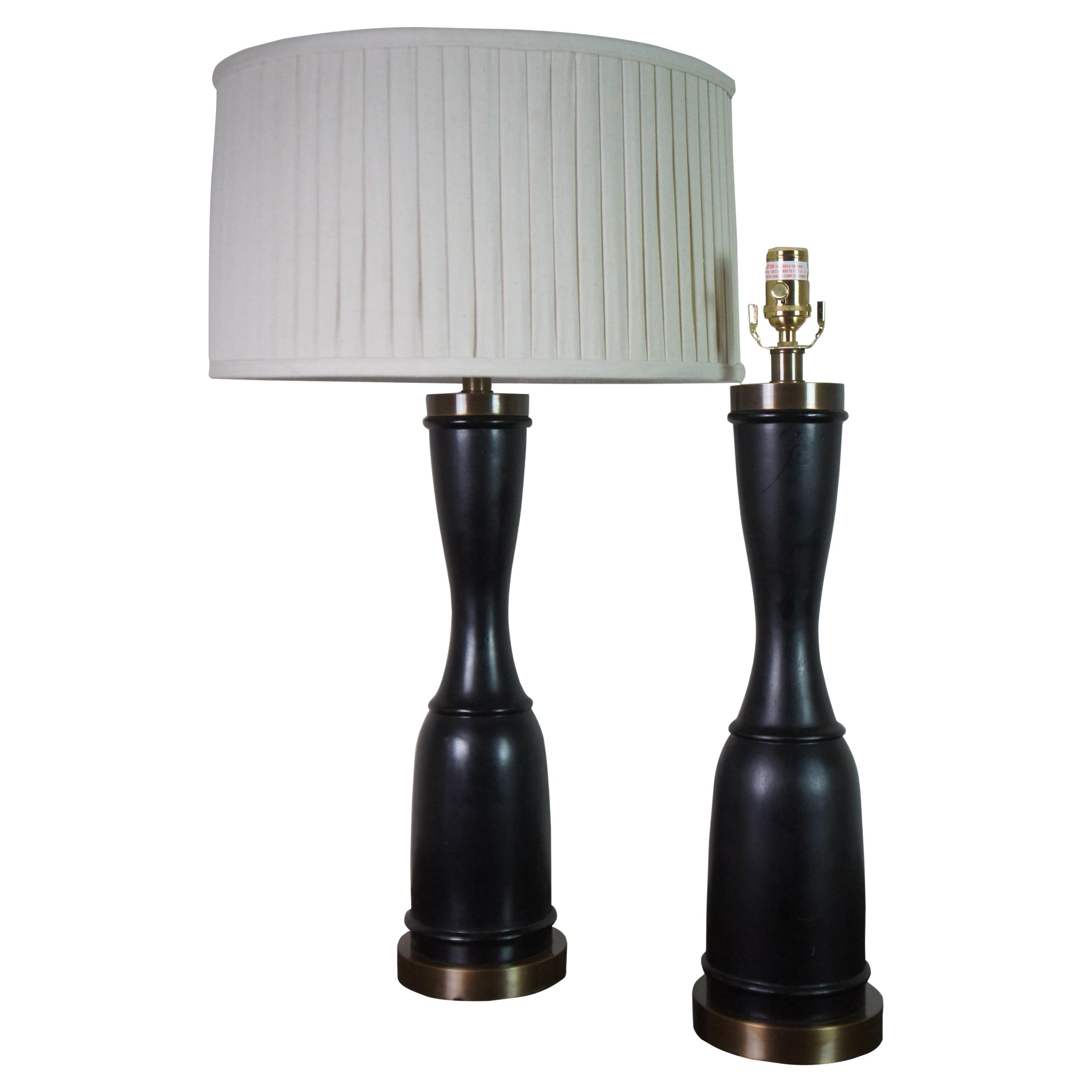 Two vintage designer table lamps featuring a turned trophy form with ebonized wood and brushed brass accents. Attributed to Baker Furniture.

Measures: 6” x 24.5” / Shade - 18.5” x 10” / Height to Top of Finial – 32” (Diameter x Height).