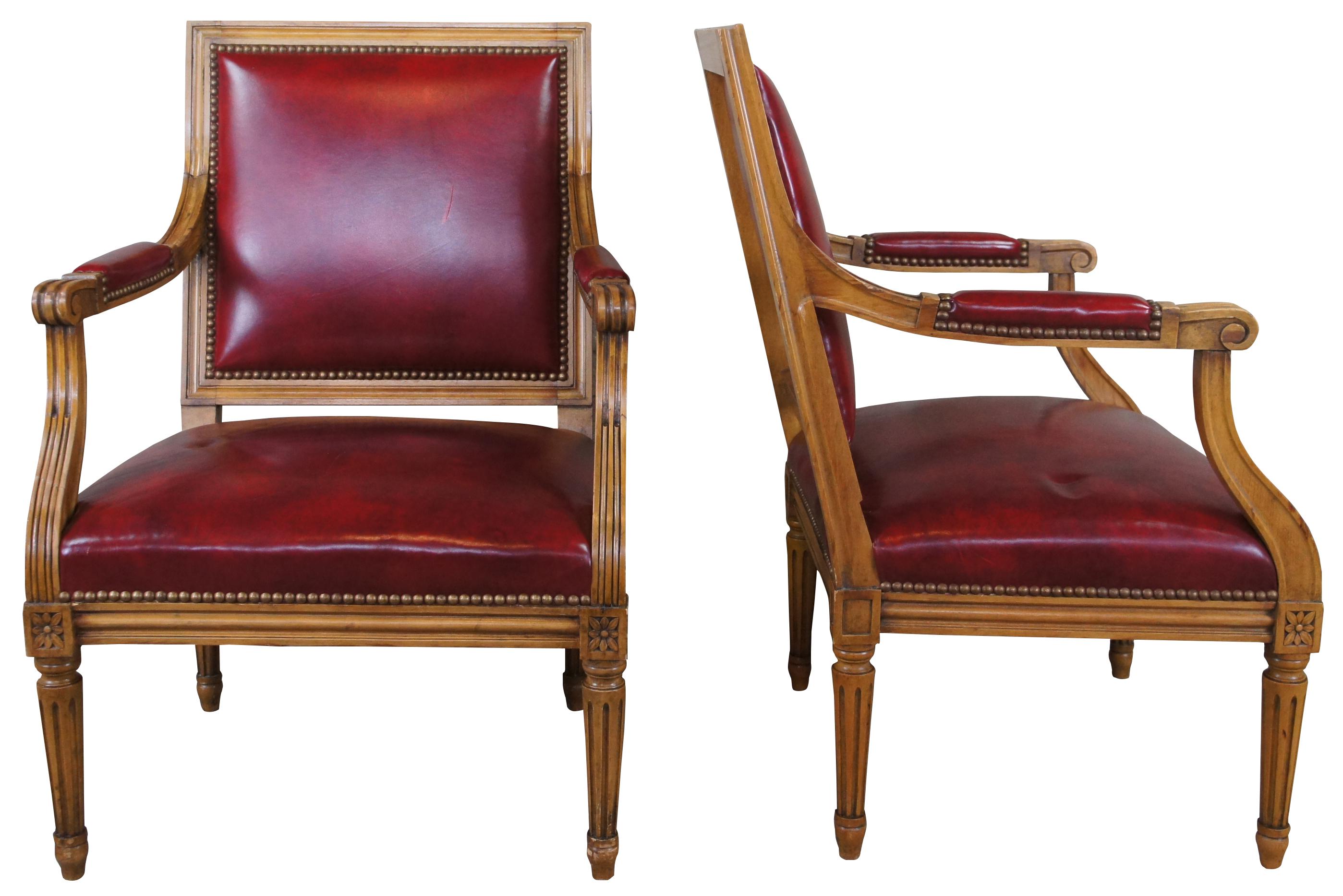 Pair of mid 20th century antique Louis XVI armchairs. Made of walnut featuring a square back leading to scrolled and fluted open arms. The apron of the chair features carved florets along the corners and is supported by fluted tapering legs that