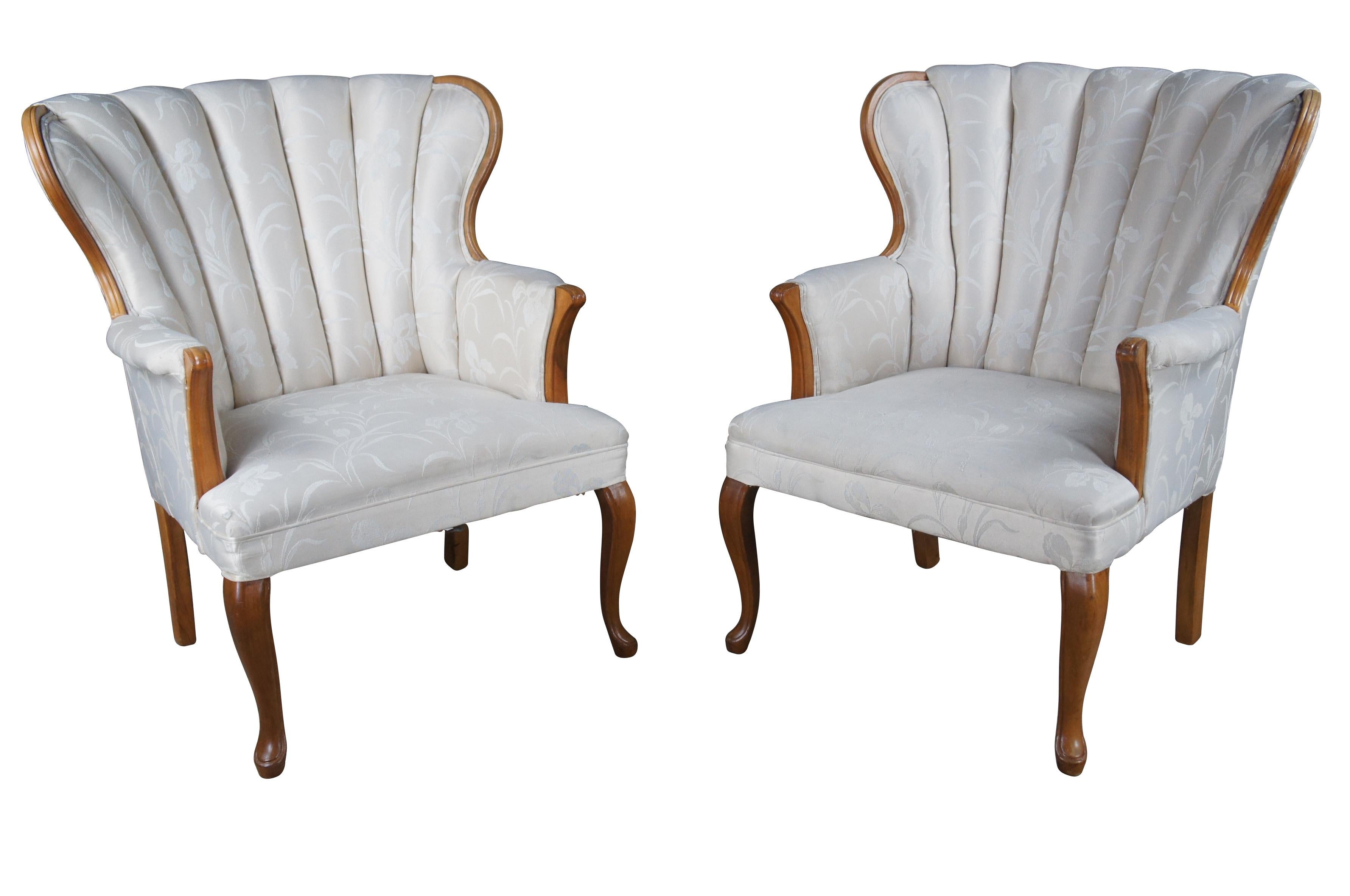 A graceful pair of mid 20th century library wingback chairs.  Made from mahogany with a raised floral upholstered channel back. The chair is supported by cabriole legs along the front and square legs at the rear.  


Dimensions:
30