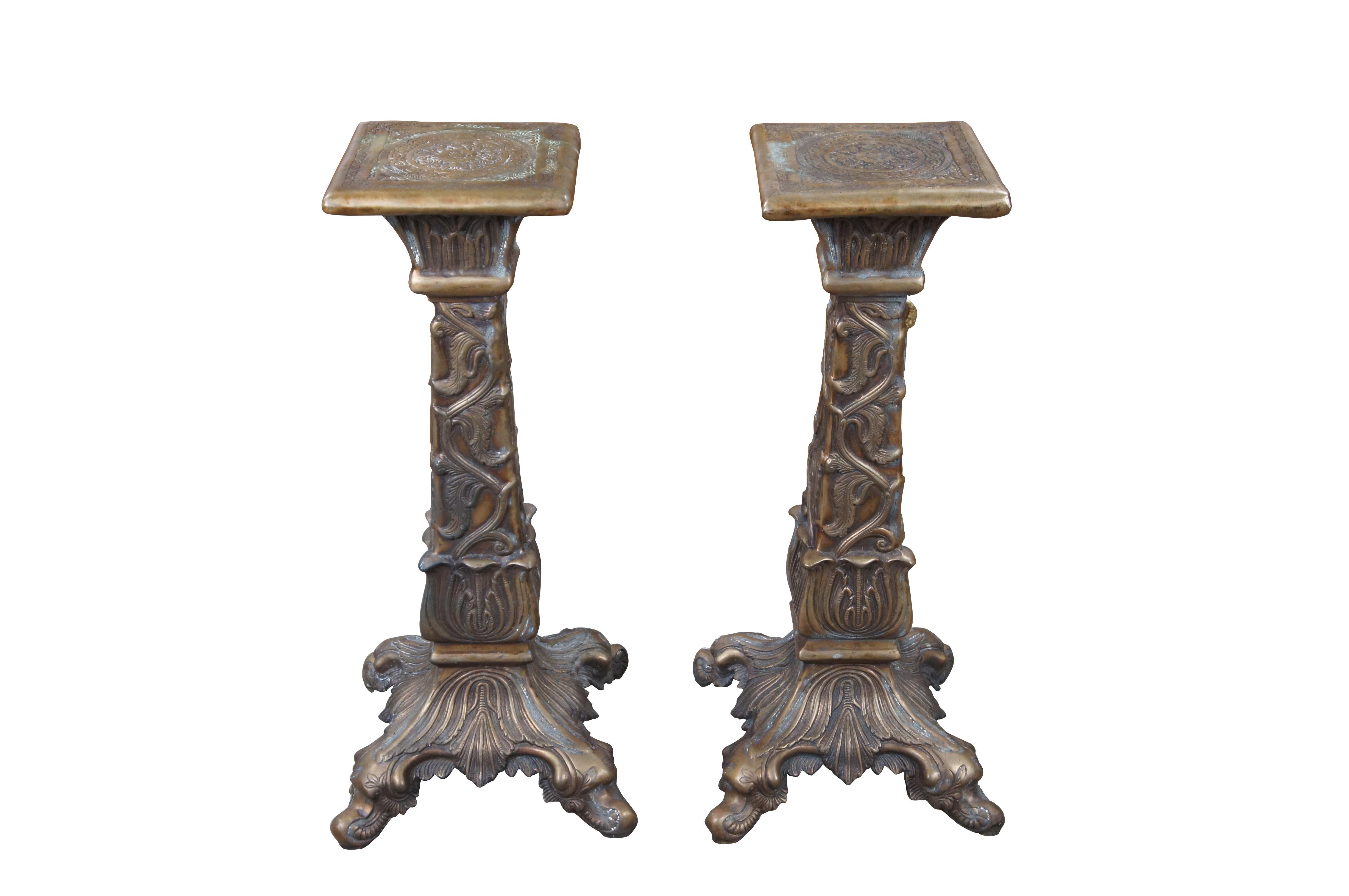 Pair bronze candle stands or sculpture pedestals. Features foliate and acanthus low relief details over an ornate four legged base. The top of each is embossed with geometric detail.

Dimensions:
12