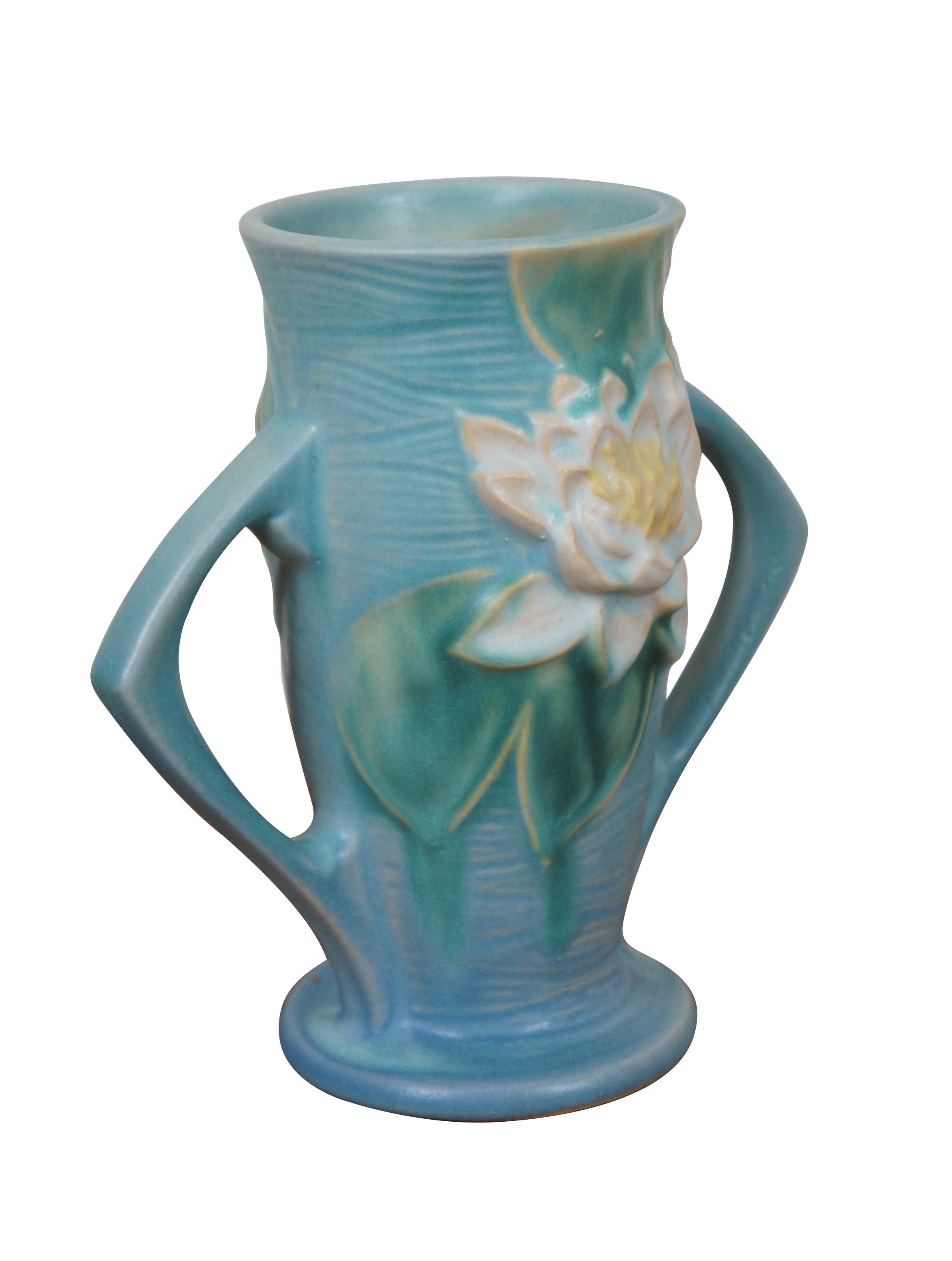 Pair of circa 1940s Roseville USA ceramic vases, number 72-6. Footed cylindrical form with triangular double handles / ears, blue water texture with water lilies / lily pads. The Water Lily pattern was introduced in 1943.

