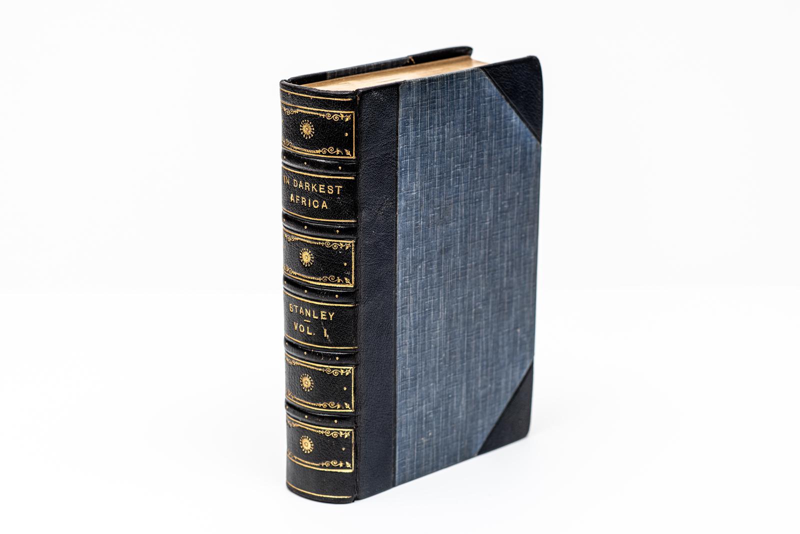 2 Volumes. Henry M. Stanley, In Darkest Africa. Third Edition. Bound in 3/4 navy morocco and linen boards. The raised band spine is gilt-tooled. The top edges are gilt with marbled endpapers. Includes 150 woodcut illustrations and maps. London: