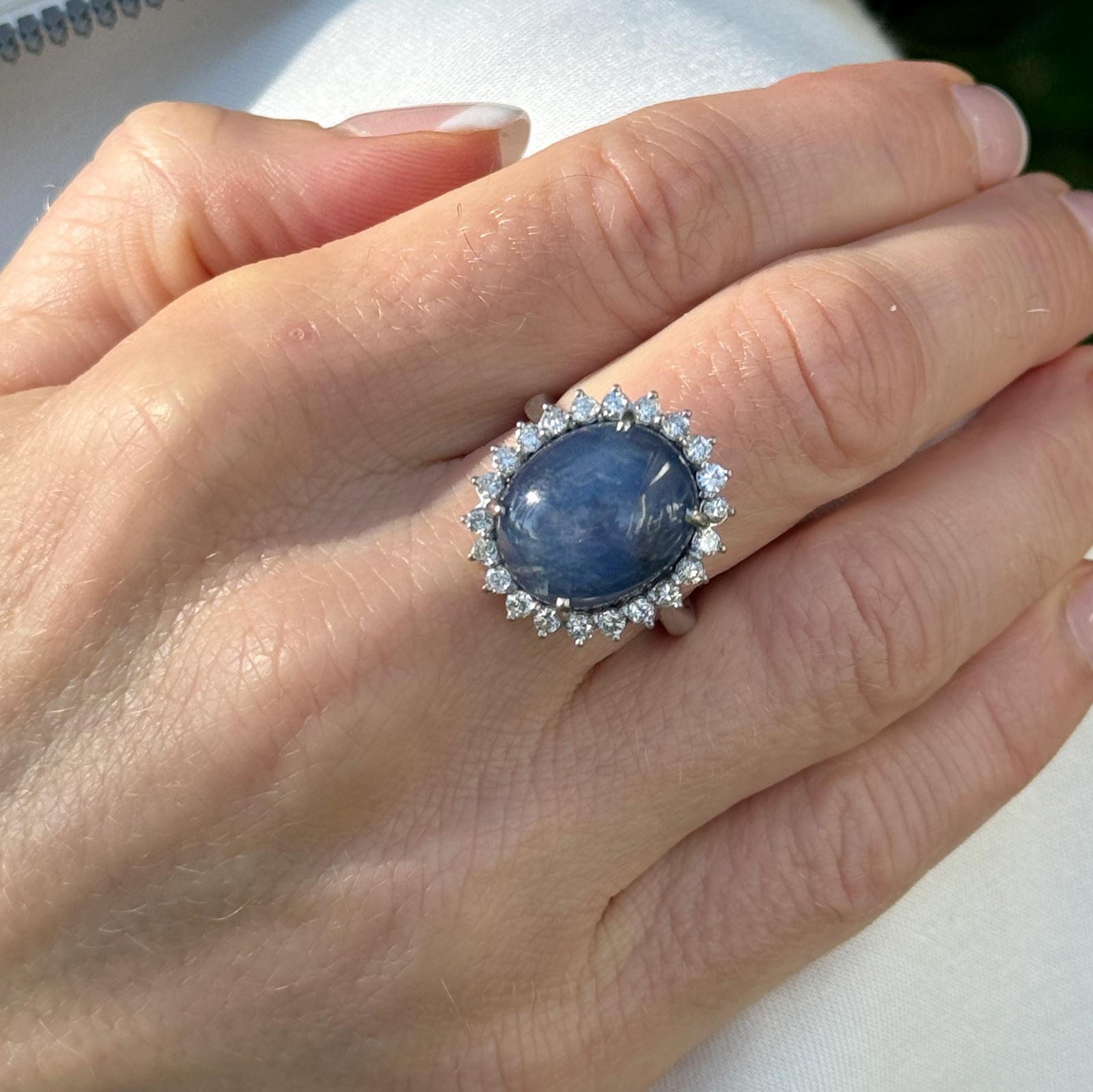 Bague de cocktail vintage en saphir bleu et diamant, réalisée en or blanc 18 carats. Le saphir bleu naturel cabochon pèse environ 20 carats et est entouré de 22 diamants ronds de taille brillant pesant environ 0,66 CTW. Les diamants sont de couleur