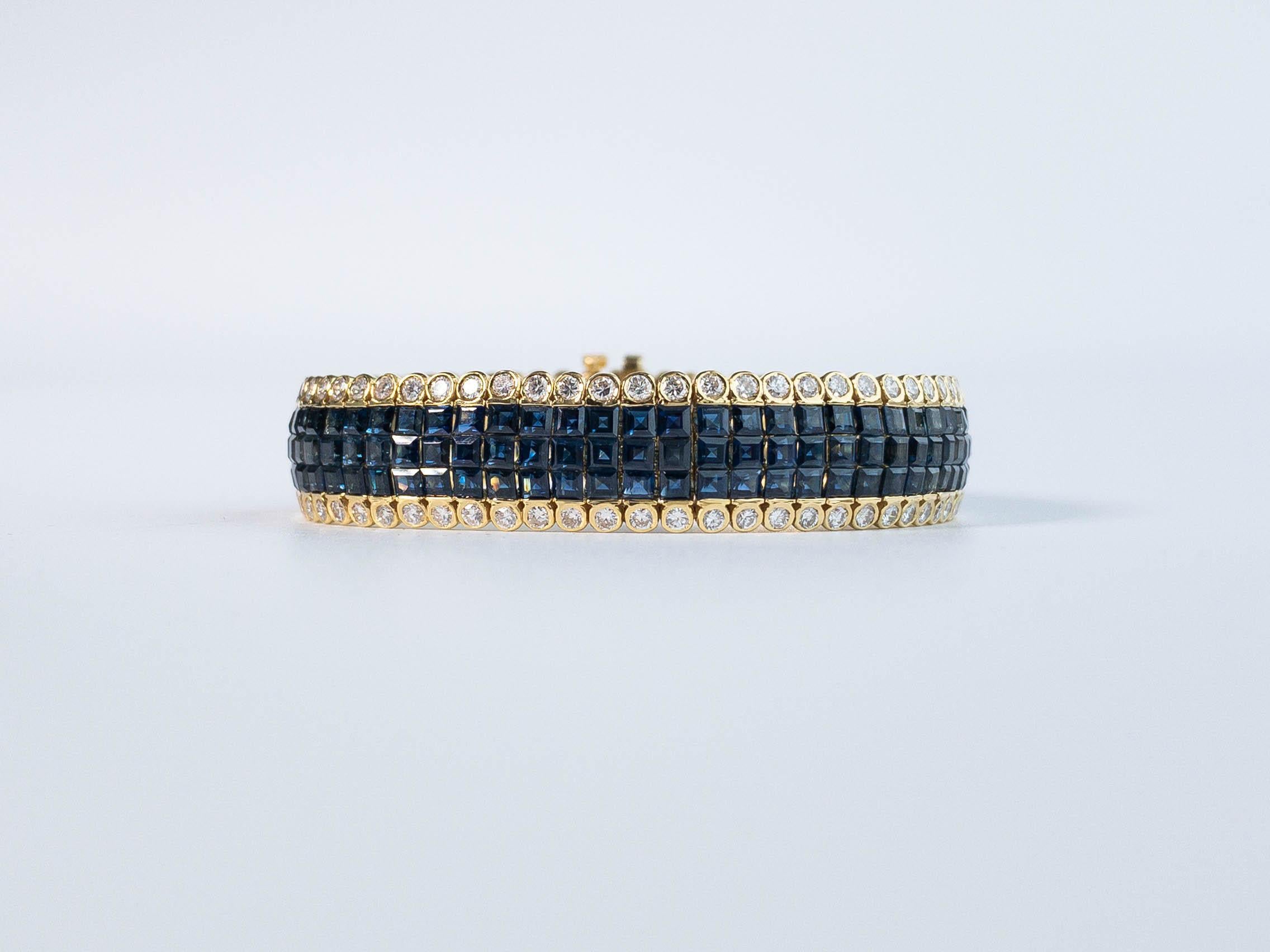 A fine blue sapphire and diamond bracelet set in yellow gold.  This lovely piece displays 204 pieces of square cut natural blue sapphires from Thailand in three rows of invisible setting and accented with 136 bezel set round white diamonds.

Blue