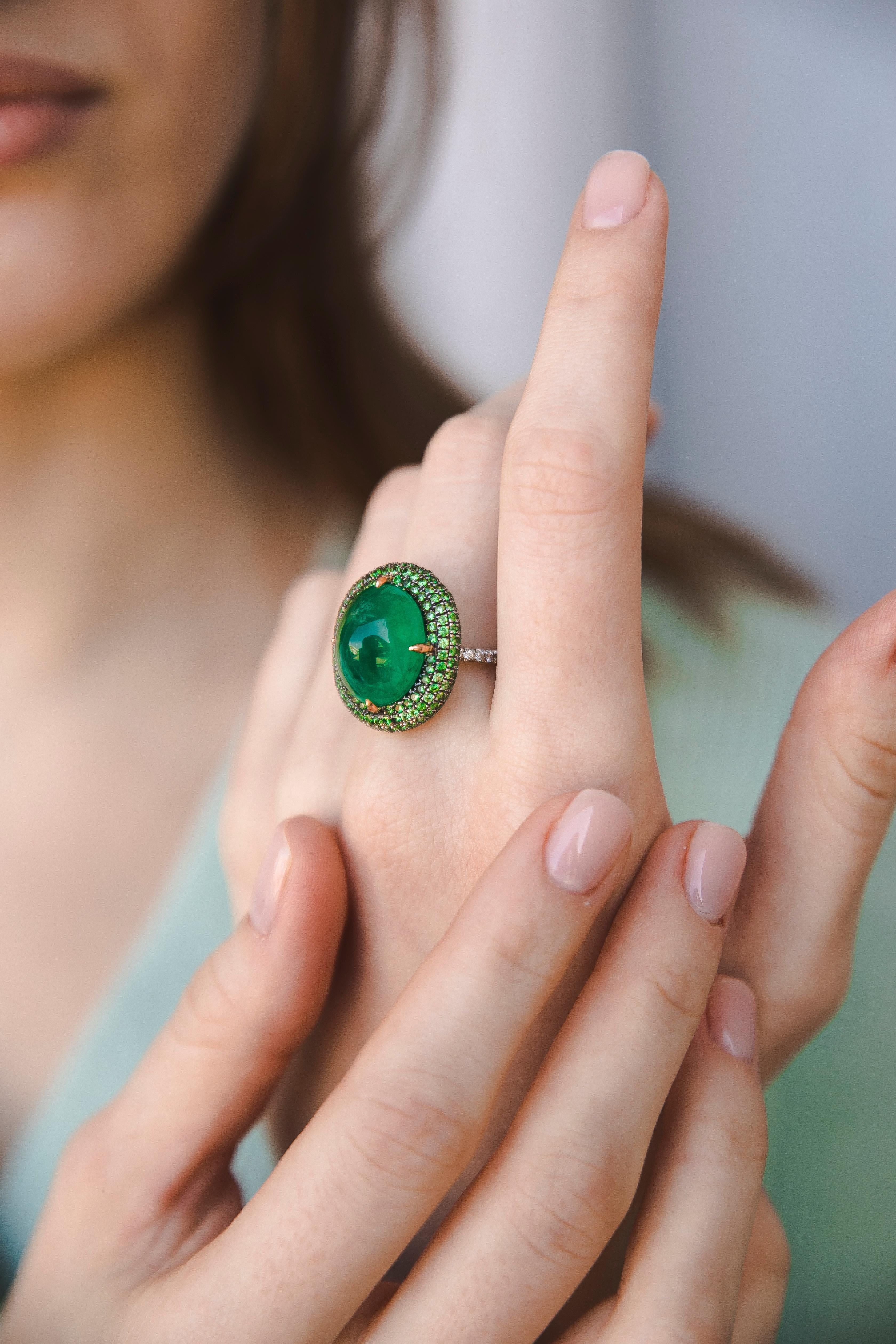 Cabochon Emerald weighting 20Ct is set with Tsavorite bright green stones and Diamonds. Fine ring of exceptional quality. 1970. 
The ring band is set with fine Diamonds. The difference of the deep green colour of the Emerald and the light eclectic