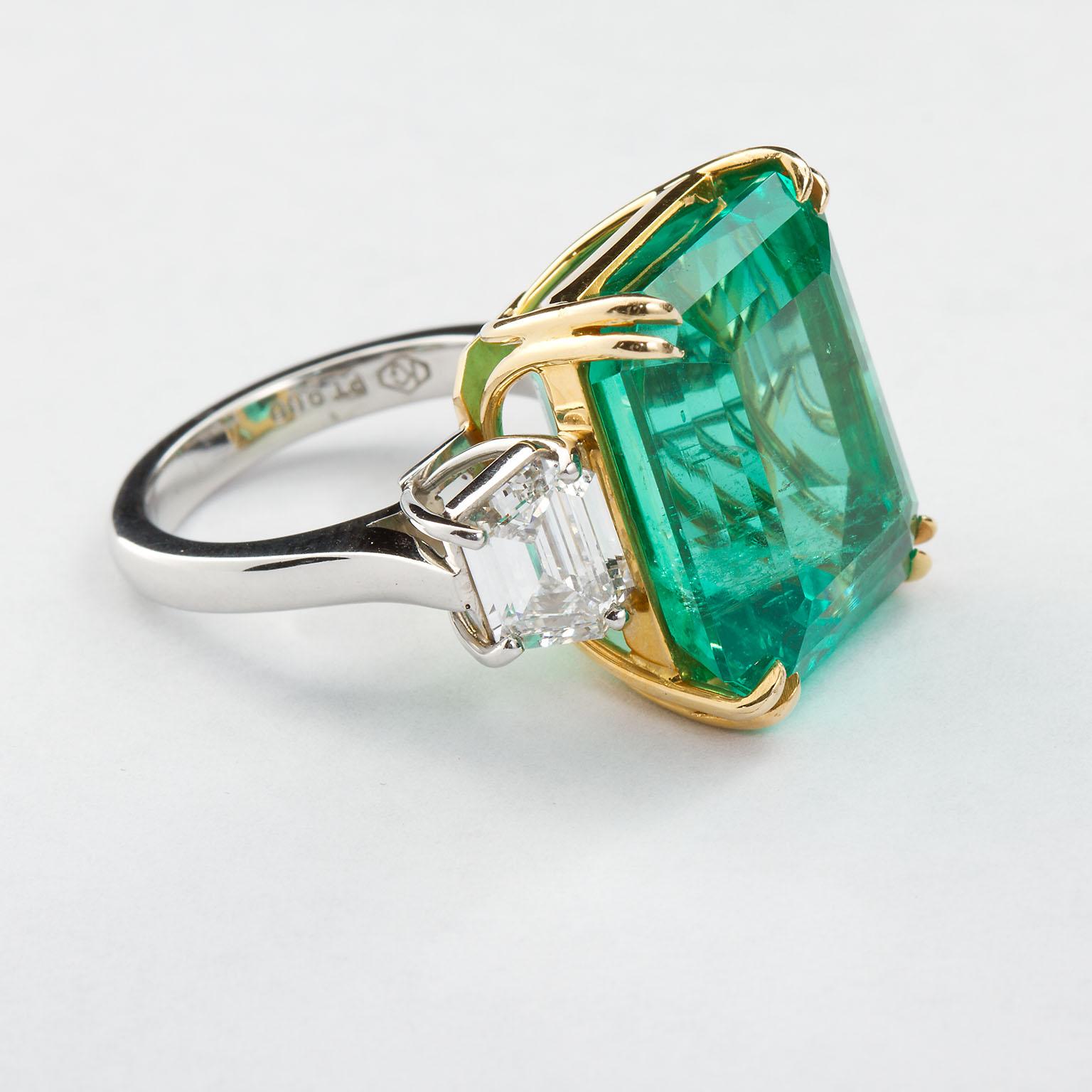 A remarkable fine Colombian emerald set in an 18k and platinum two diamond side-stone ring. The 22.54 carat emerald shows very good color being deep green and highly transparent. Slight threading towards the bottom and side of the table. Set between