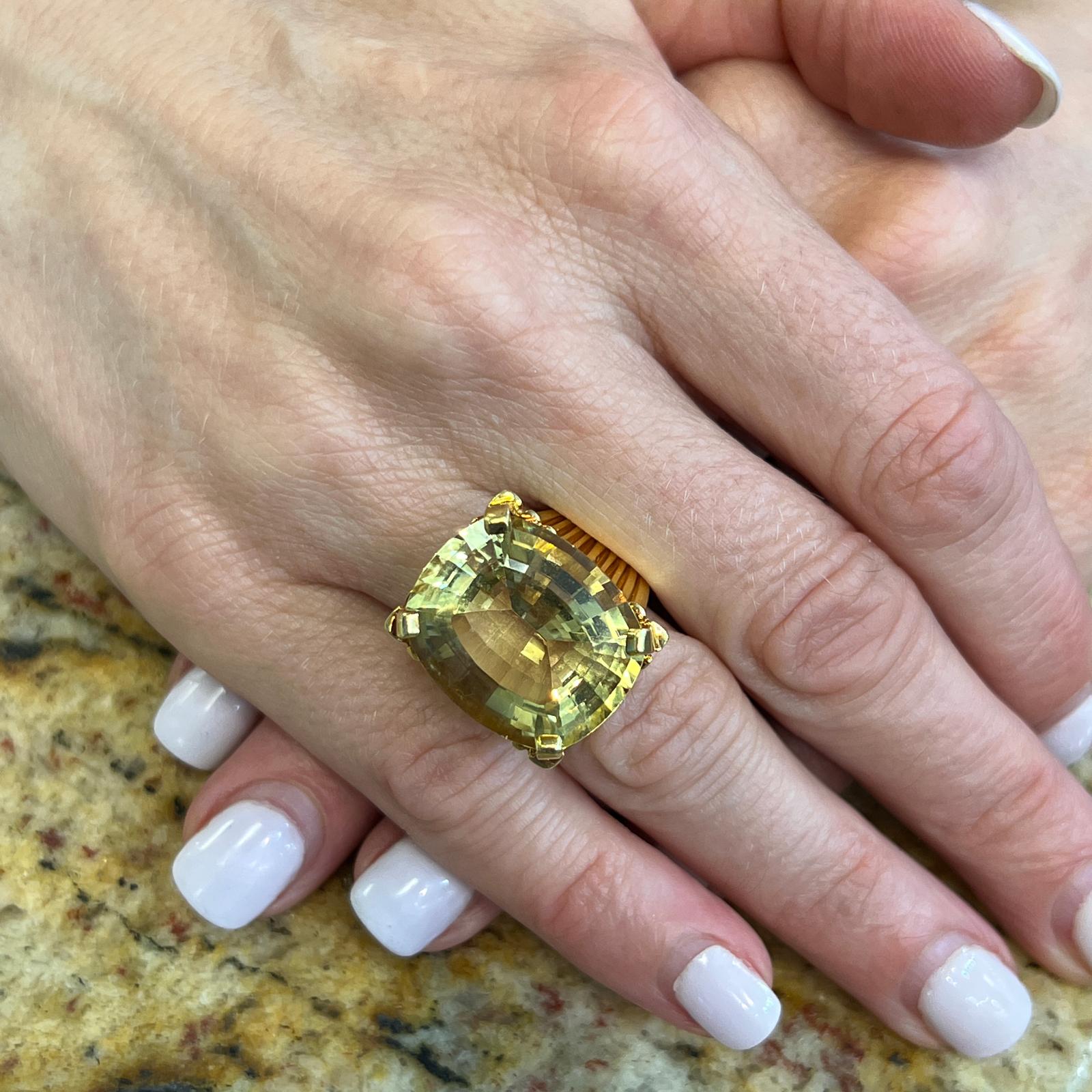 Fabulous 1960's lemon citrine cocktail ring fashioned in 18 karat yellow gold. The ring features a faceted cushion cut lemon citrine gemstome weighing approximately 20 carats. The citrine is prong set in a ribbed retro style yellow gold mounting. 
