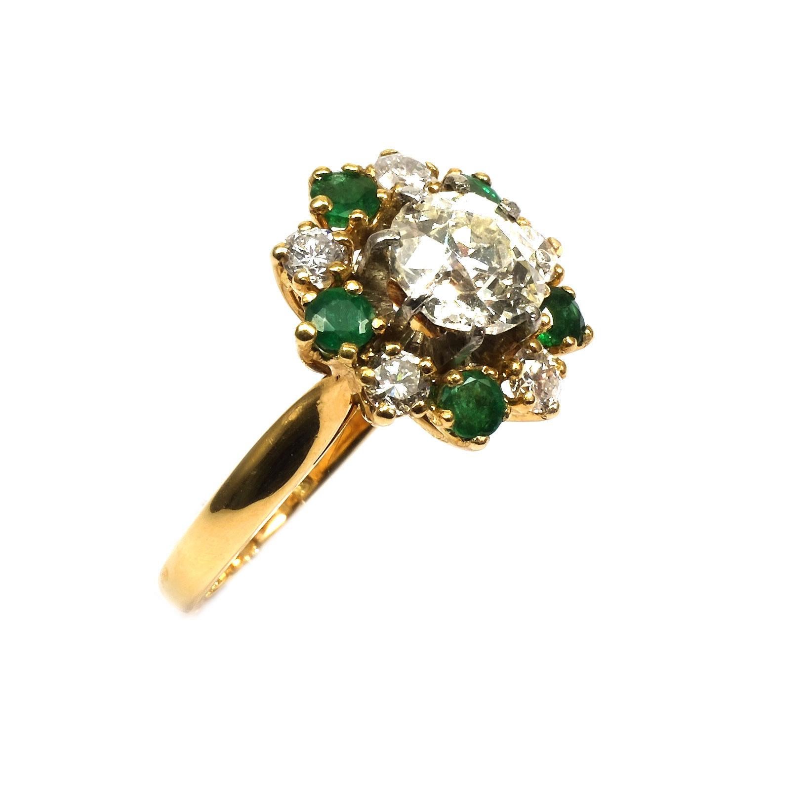 2.0 Carat Diamond and Emerald 18 K Yellow Gold Cluster Ring Paris circa 1930

Decorative diamond ring with a flower-shaped ring head, set with an old European-cut diamond of 1.55 ct in an entourage of emeralds and 5 brilliant-cut diamonds totaling