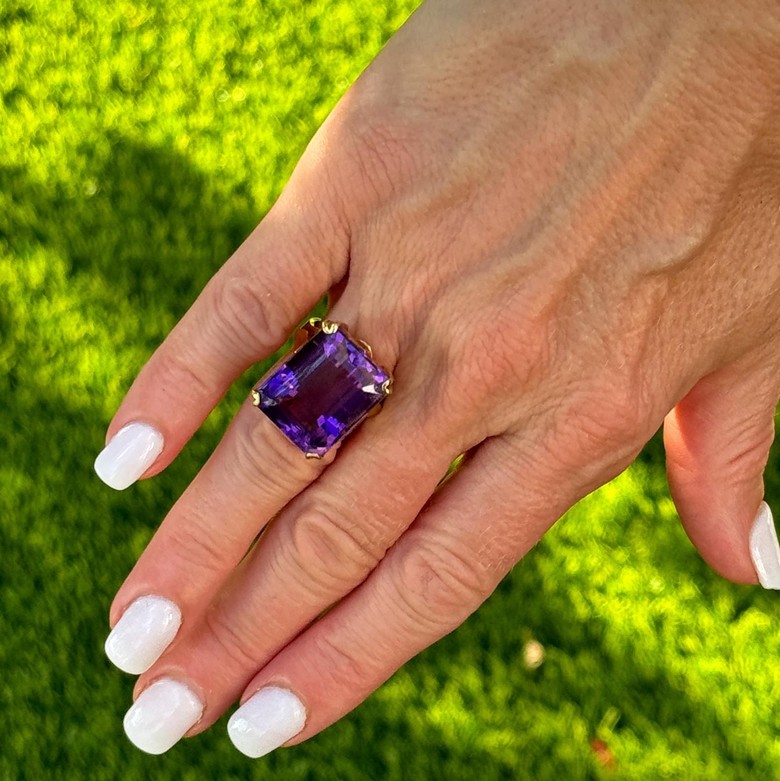 Vintage amethyst cocktail ring handcrafted in 18 karat yellow gold. The emerald cut natural purple amethyst gemstone weighs approximately 20 carats and is set in a beautiful vintage mounting. The ring measures 15 x 20mm and is currently size 6 (can