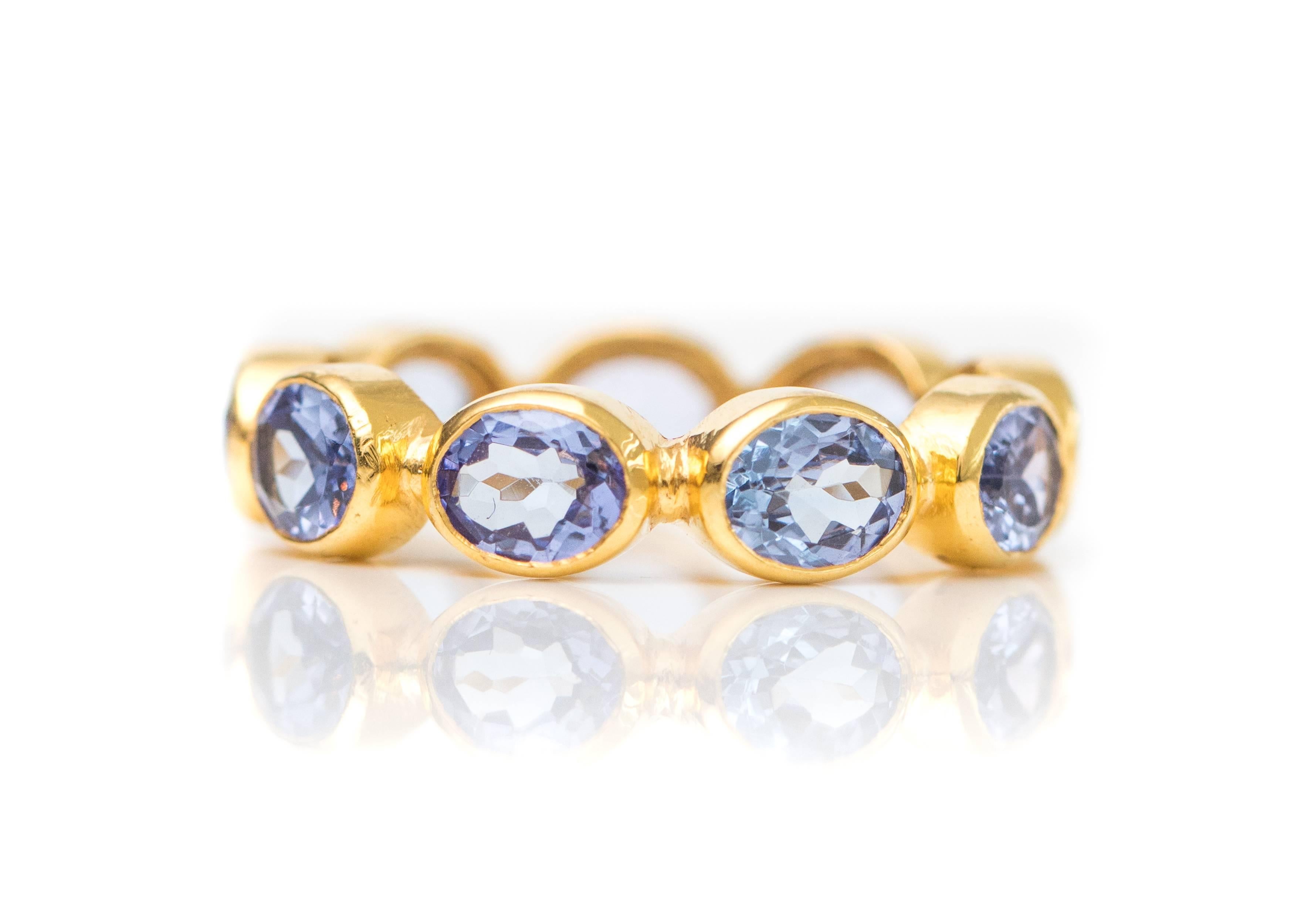 2.0 Carat Tanzanite and 18 Karat Yellow Gold Eternity Band

Features a ring of Violet Blue Tanzanite in 18 Karat Yellow Gold. The Oval Brilliant gemstones are set in an East-West direction. Each stone is bezel set in 18 Karat Yellow Gold. The sides