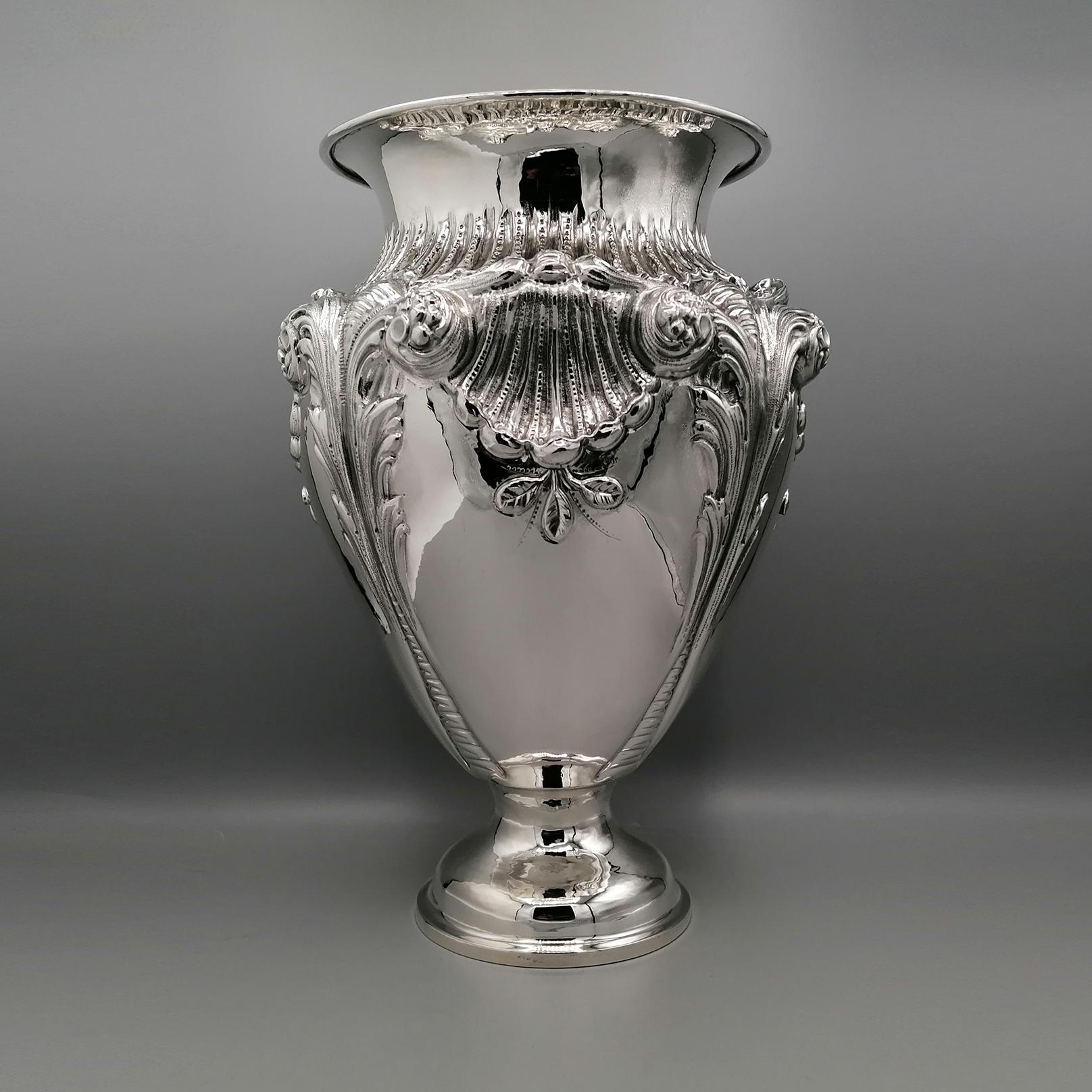 Large baroque style sterling silver vase.
The body of the vase has been masterfully embossed with shells, flowers and volutes, typical of the Baroque style.
Still in the body of the vase, some parts have been left shiny to highlight the great