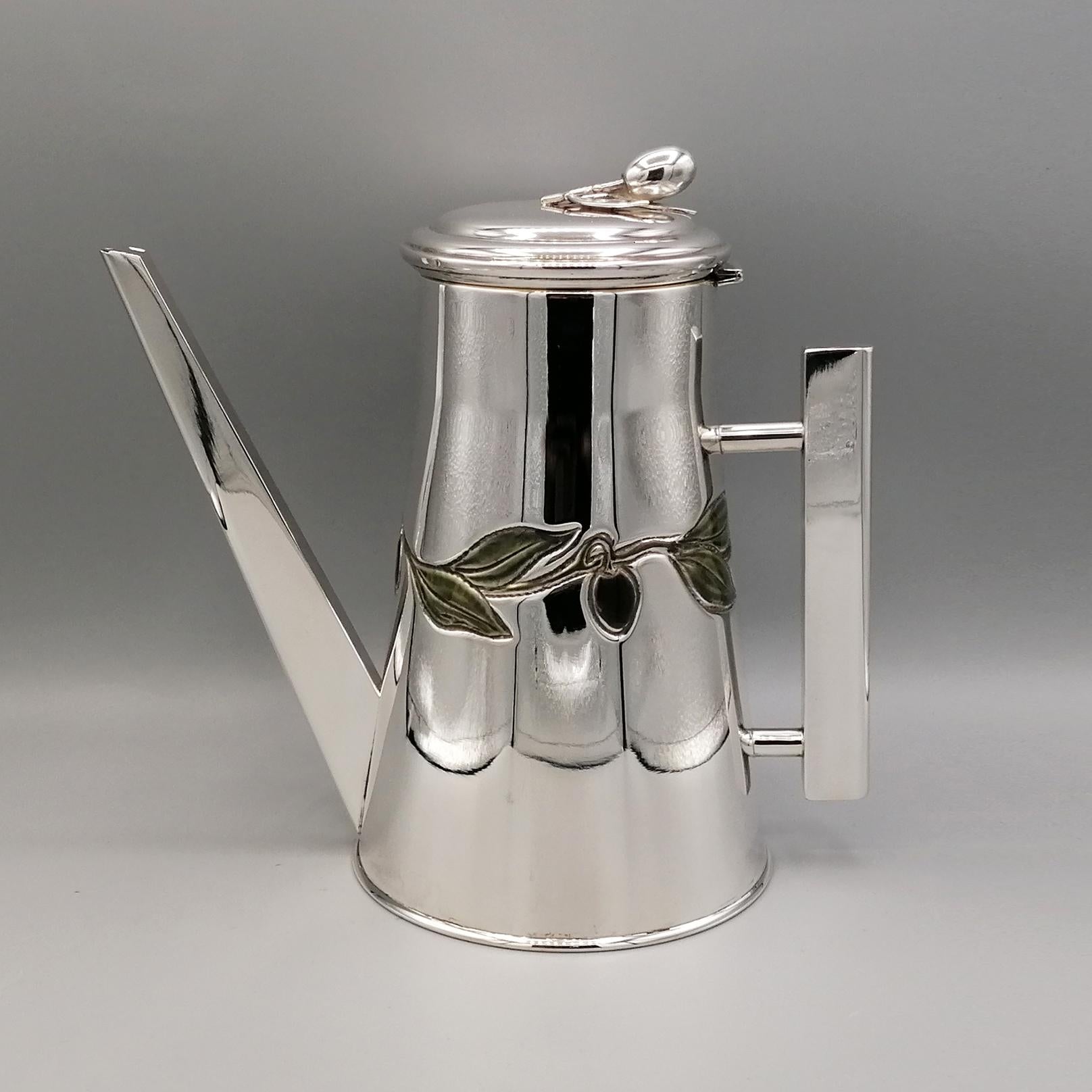 Sterling silver oil cruet.
The conical body of the cruet is smooth and shiny.
In the central part, olives and olive leaves were embossed and subsequently fired enamelled.
The spout and the handle are square in shape making the whole object very