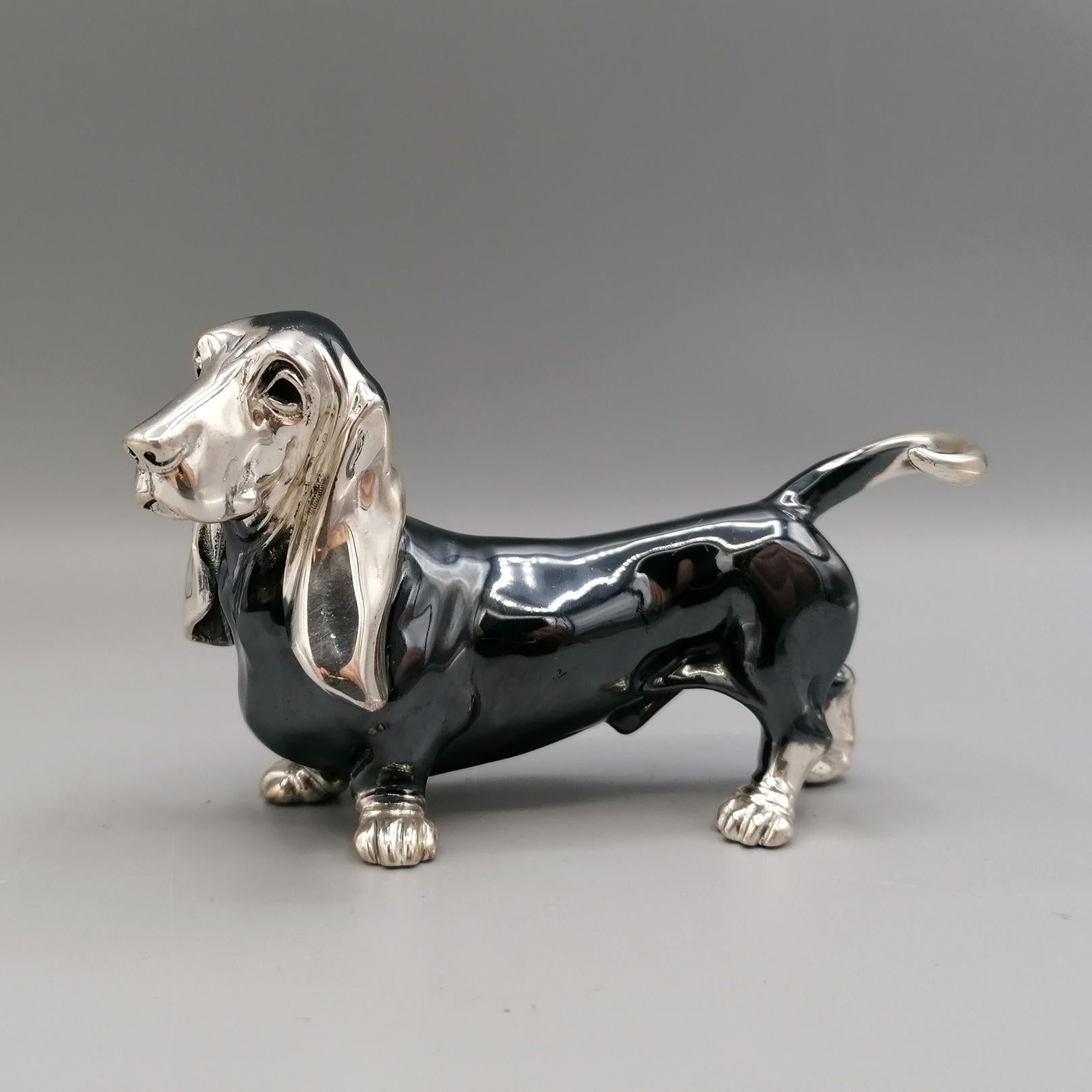 Basset Hound Hundestatuette aus massivem 800er Silber.
Das Objekt wurde mit der Technik des Schmelzens in zwei Hälften hergestellt und anschließend durch Schweißen verbunden. 
Im unteren Teil der Statuette sind die beiden Löcher zu sehen, durch die