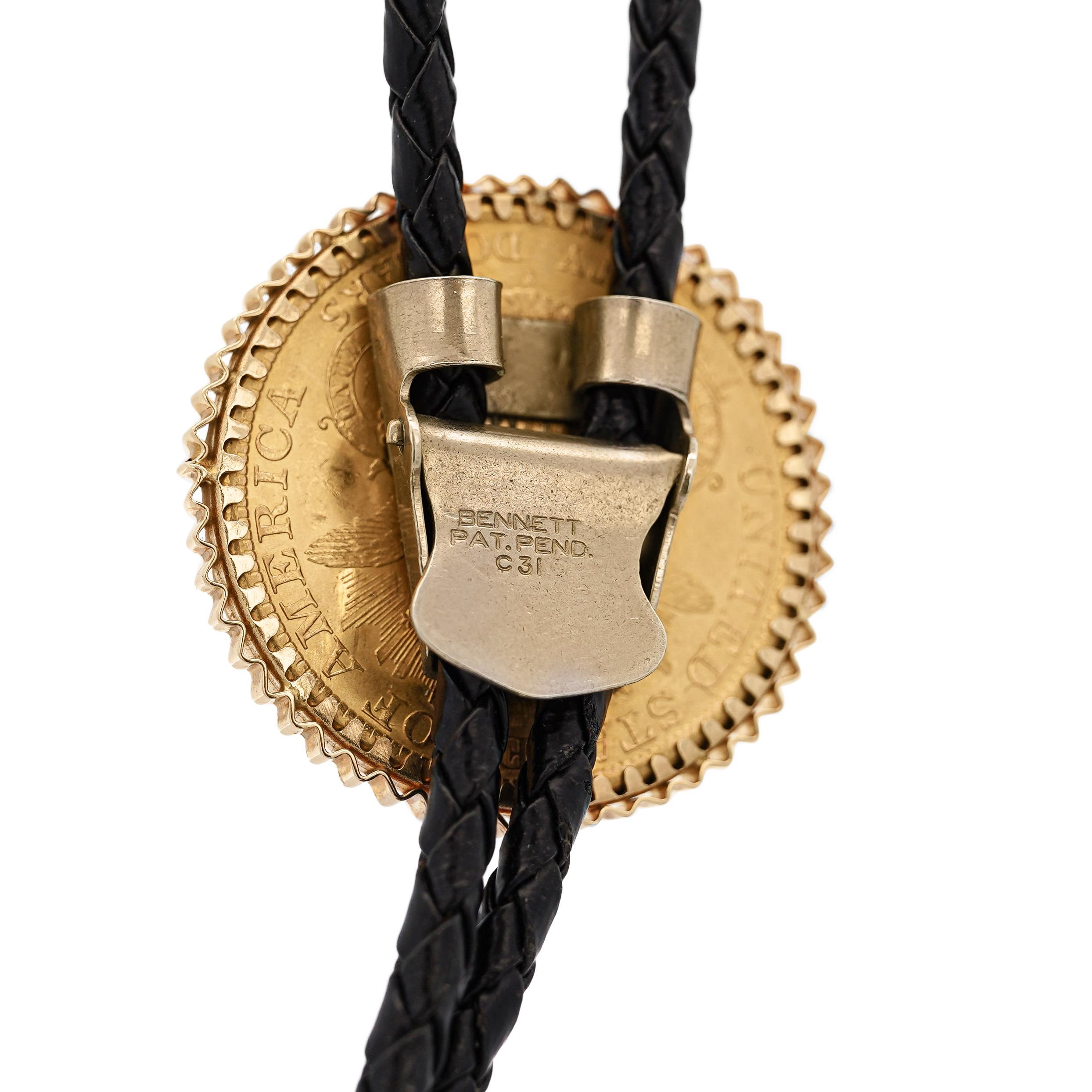 Cette cravate unique 14K Coin Bolo Tie met en valeur une authentique pièce de 20 $ Liberty Gold Double Eagle MS-63 de 1899. La cravate bolo en or 14 carats se compose d'un cordon tressé noir avec des pointes dorées et un fermoir solide, ce qui en