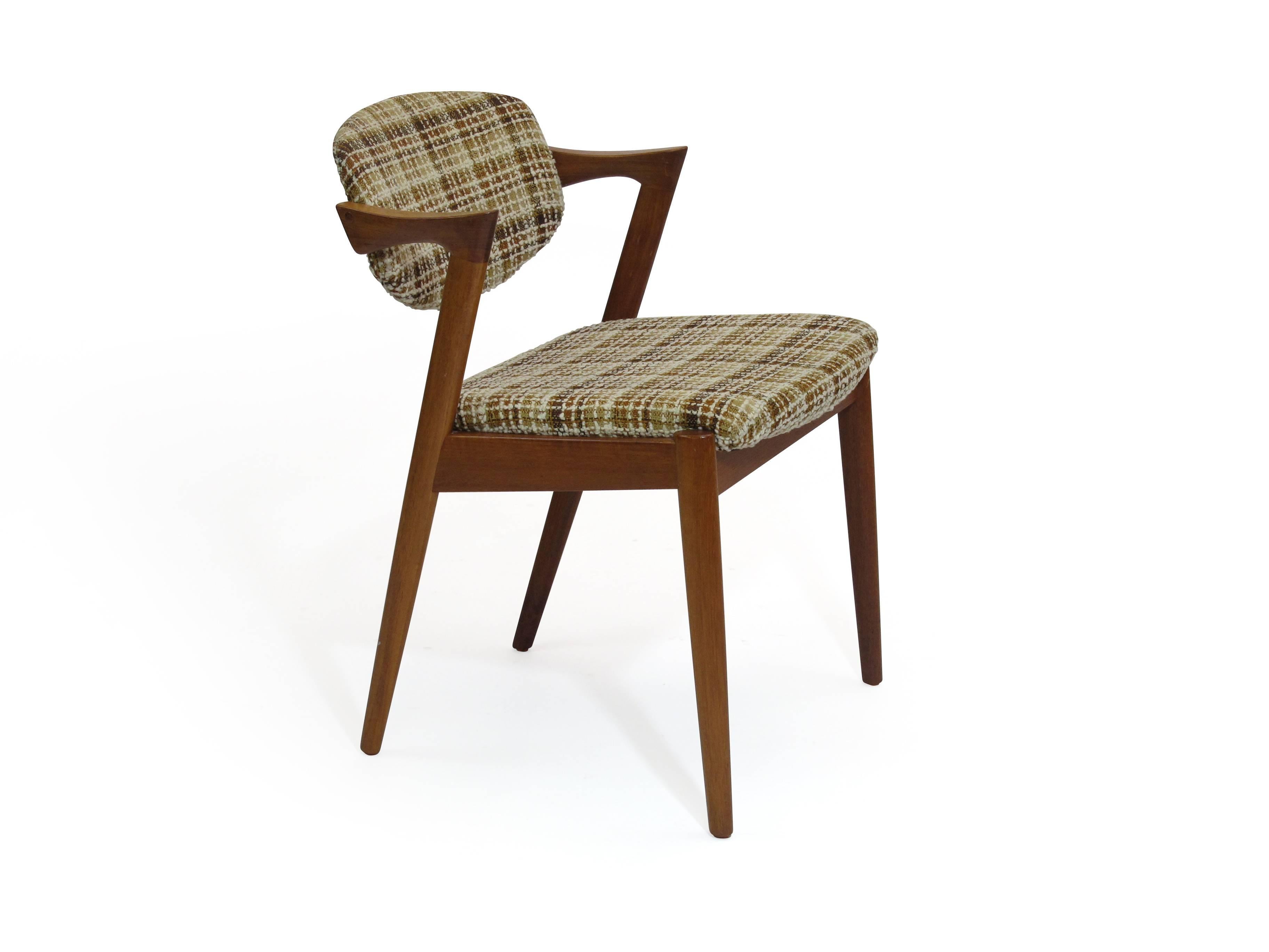 Set of four model #42 teak dining chairs designed by Kai Kristiansen. Solid teak frames with tilting back rest, angled arm rest upholstered in the original vintage fabric. Comfortable chair with modern architectural design. This listing is for 4