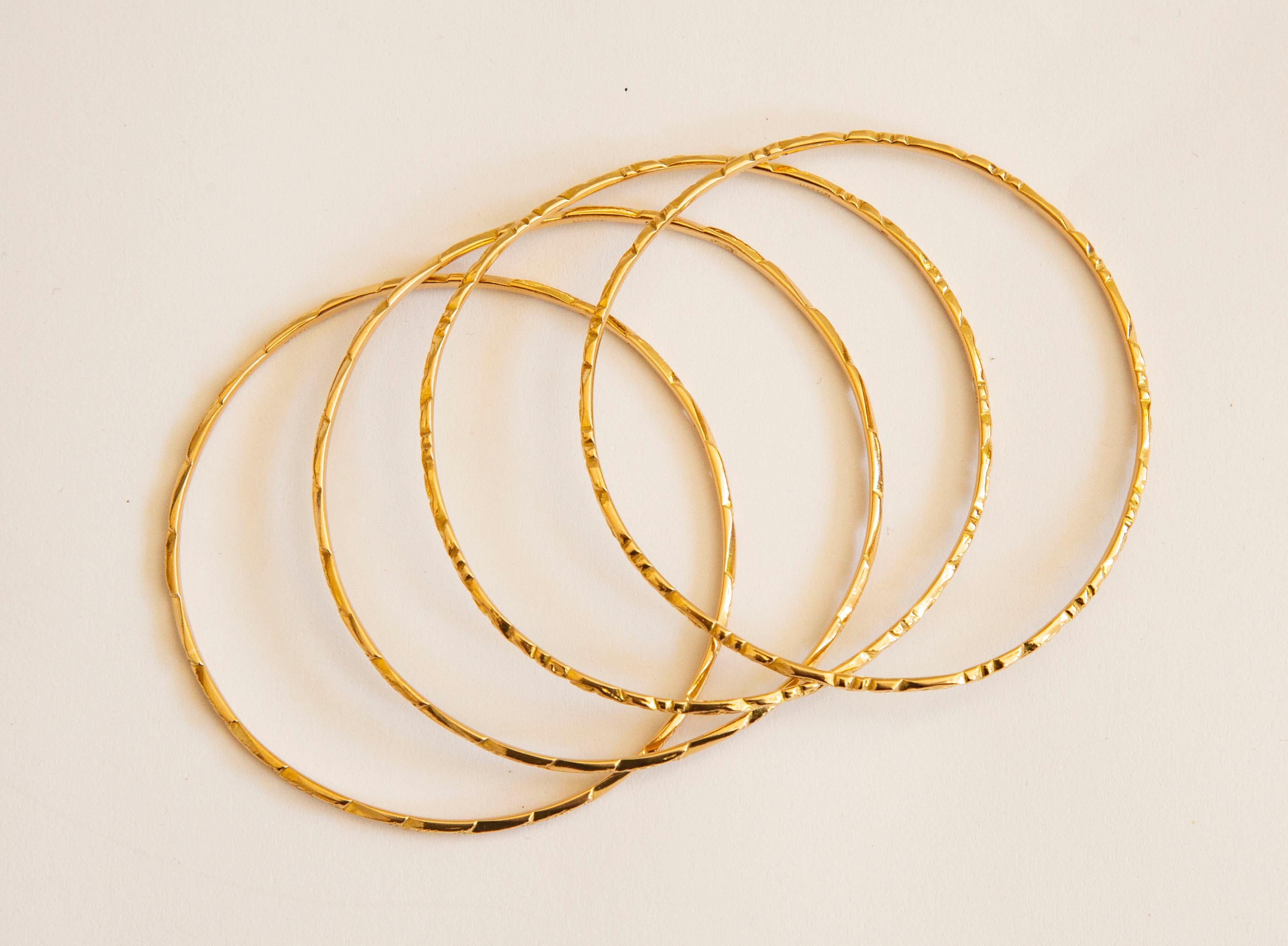 A vintage set of four bangle bracelets made of 20 karat yellow gold. The bracelets feature an engraved tow types of floral decoration on the outer surface. Two bangles feature 1 type of the decoration and the other two has the second type of the