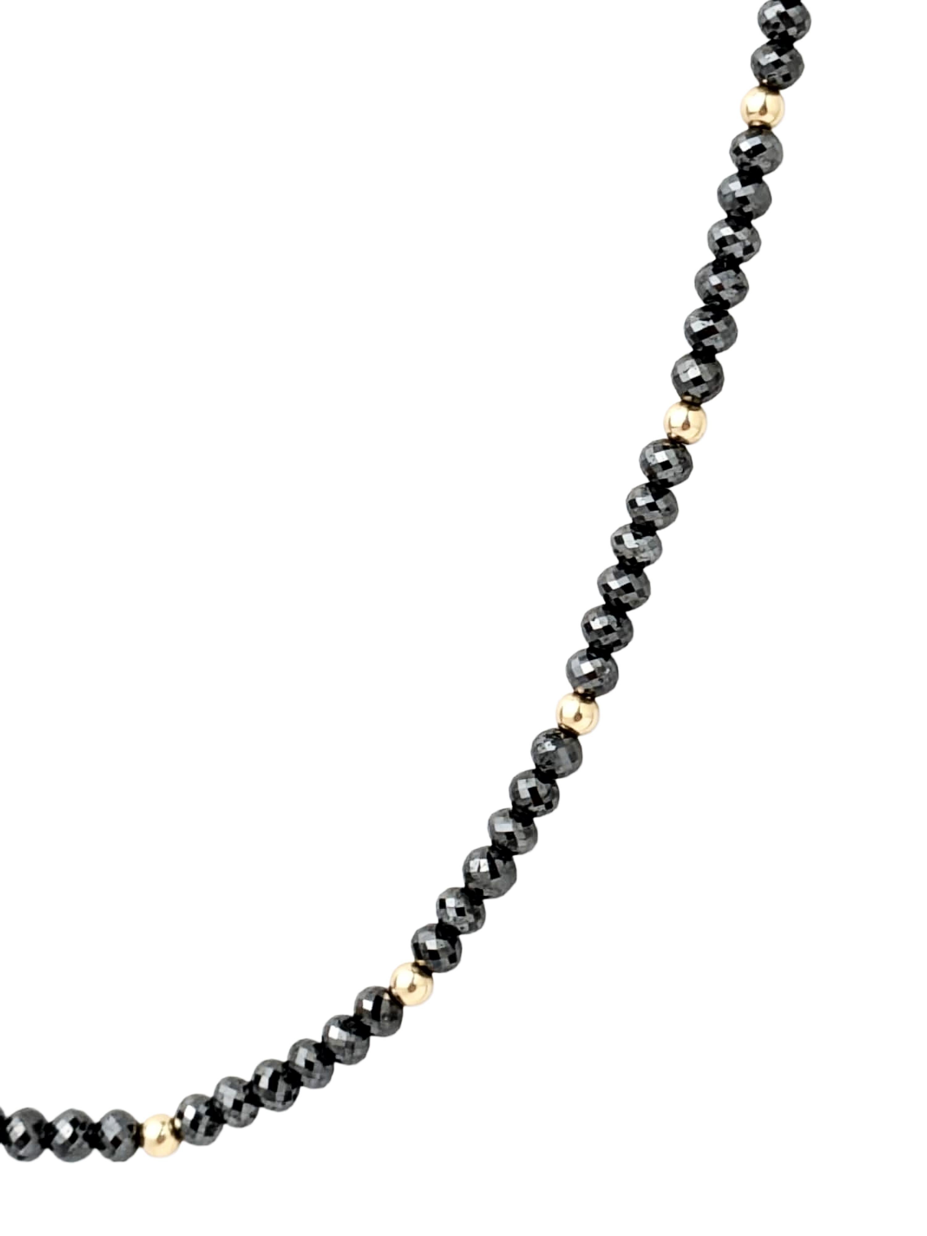 Un'espressione elegante del lusso moderno. Questo filo presenta perle di diamanti neri rotondi sfaccettati che catturano la luce da ogni angolazione, creando un raffinato gioco di brillantezza. Elegata con perline in oro giallo 14K e rifinita con