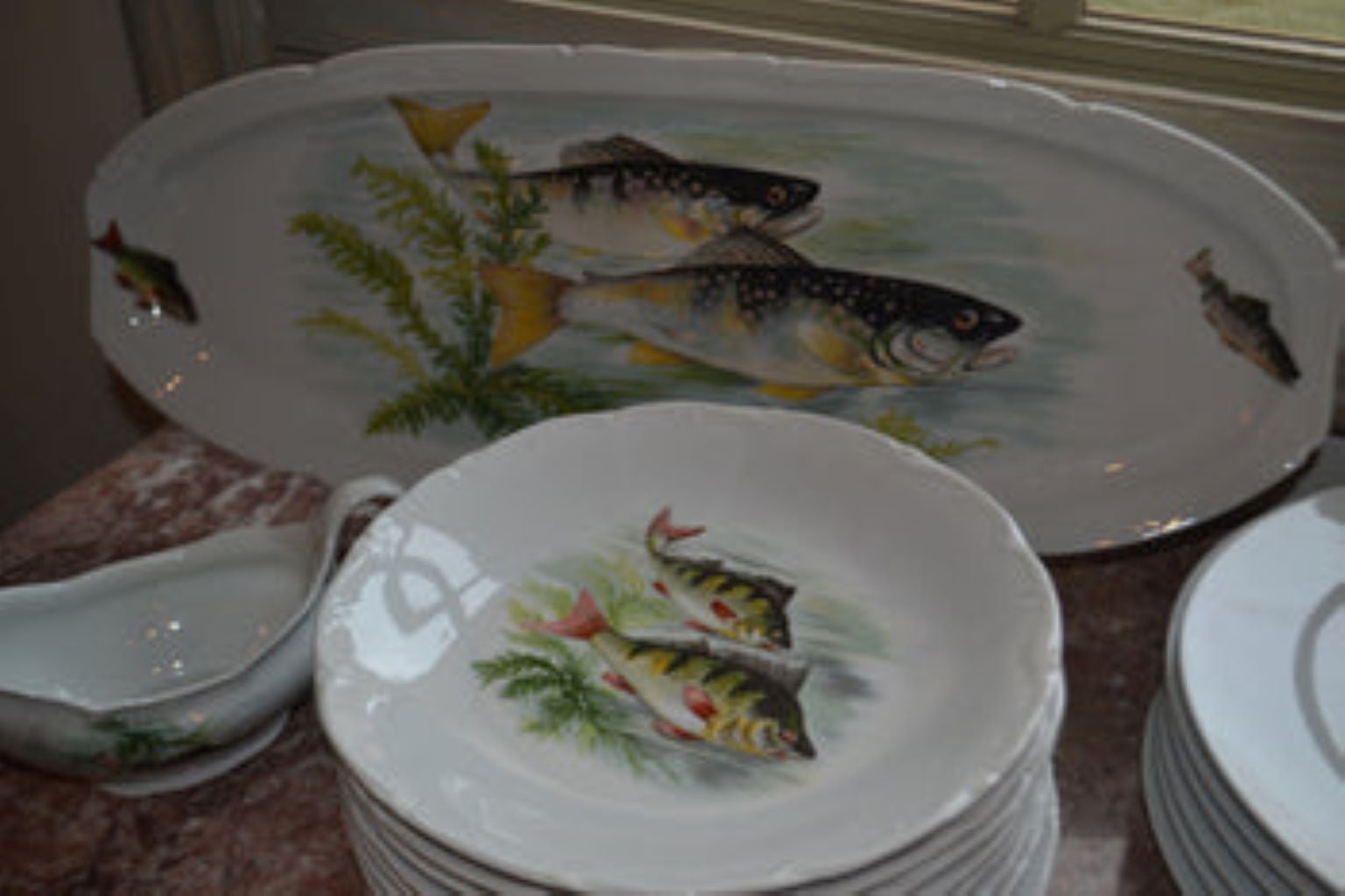 20 Piece French Porcelain fish set. 20th century, consisting of a fourteen piece set by Porcelaines de Sologne, comprised of 12 plates, and Oval platter and a sauce boat, together with 6 associated large plates by Porcelaine de Limoges, each with