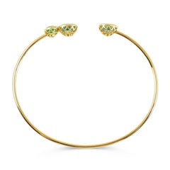 Brazalete abierto de oro amarillo de 18 quilates de 2,00 y 0,55 quilates de apatitas y esmeralda