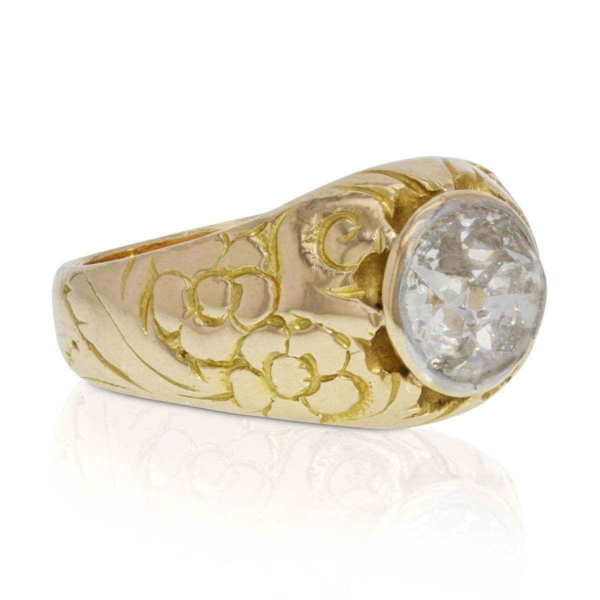 An early 20th century round cut old minor diamond meets 19th century Victorian style in this mid-century interpretation of solitaire gent's ring. Crafted in 18k yellow and intricately hand-engraved with a stylish floral design, the high-polished