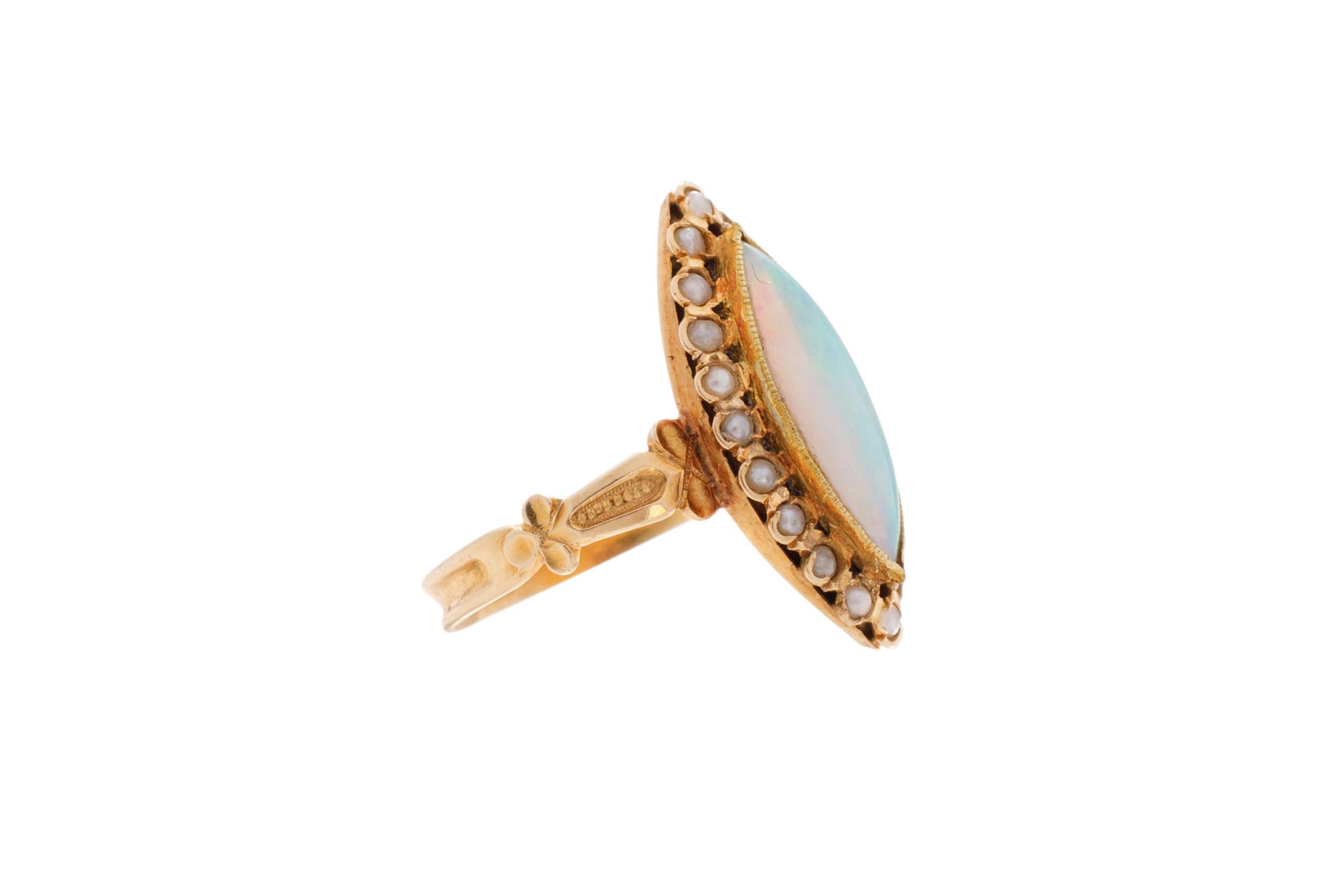 Ring Size: 5.75
Metal Type: 18 karat Yellow Gold [Hallmarked, and Tested]
Weight: 3.0 grams

Center Stone Details:
Weight: 2.00 carat
Cut: Marquise Cabachon
Type: Opal

Side Stone Details:
Weight: .75 carat
Cut: Round
Type: Natural seed