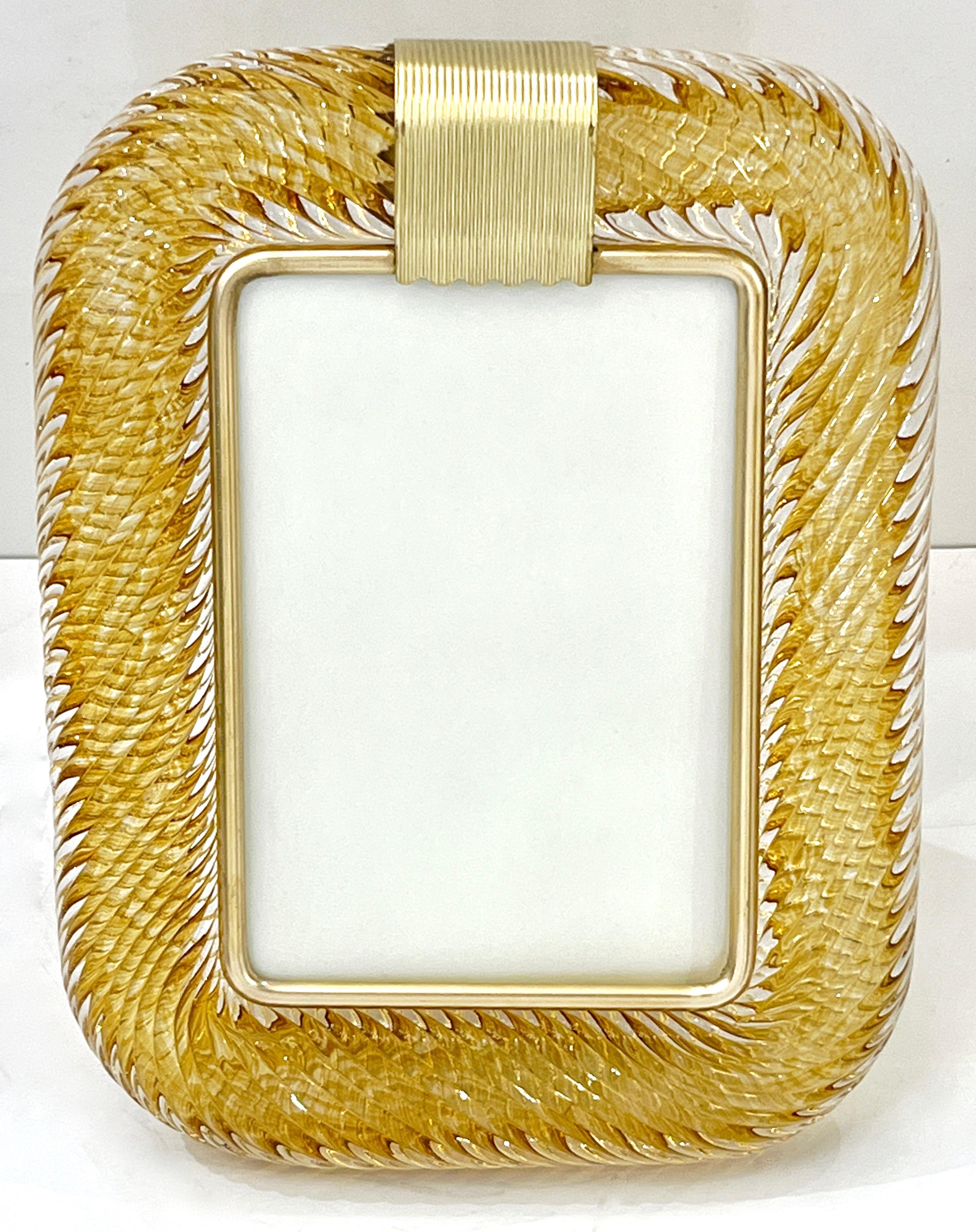 A sophisticated Venetian modern design vertical photo frame in thick blown Murano glass worked in a amber orange gold color, overlayed in crystal, by Barovier Toso Murano, signed piece. The elegant texture of the tightly twisted glass frame in