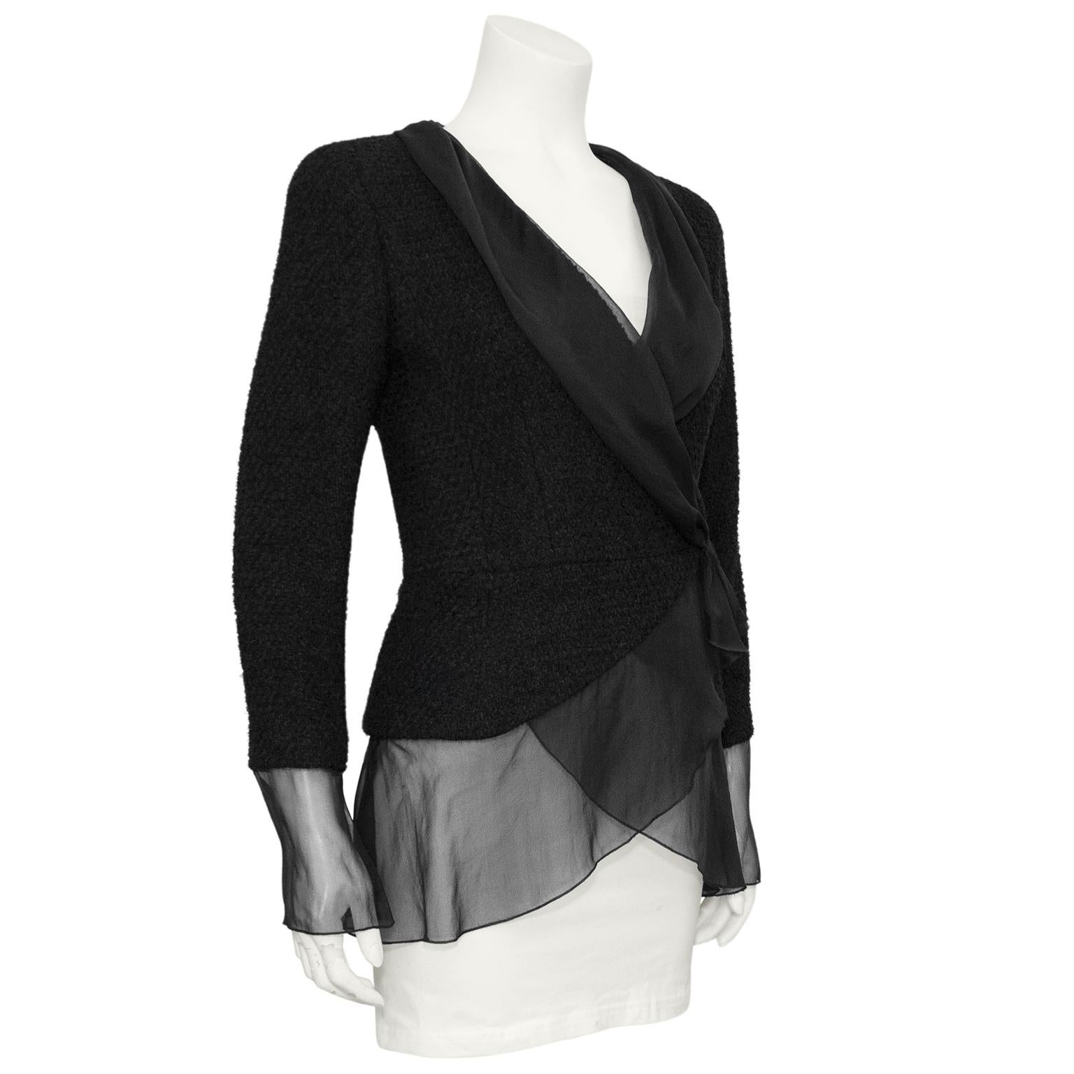 From the 2000 Transition collection, this black Chanel blazer features chiffon trim, cuffs and tuxedo style lapel. The black boucle body is fitted in the arms and nips in at the waist. Fastens at the navel with a hidden hook and eye and snap. In