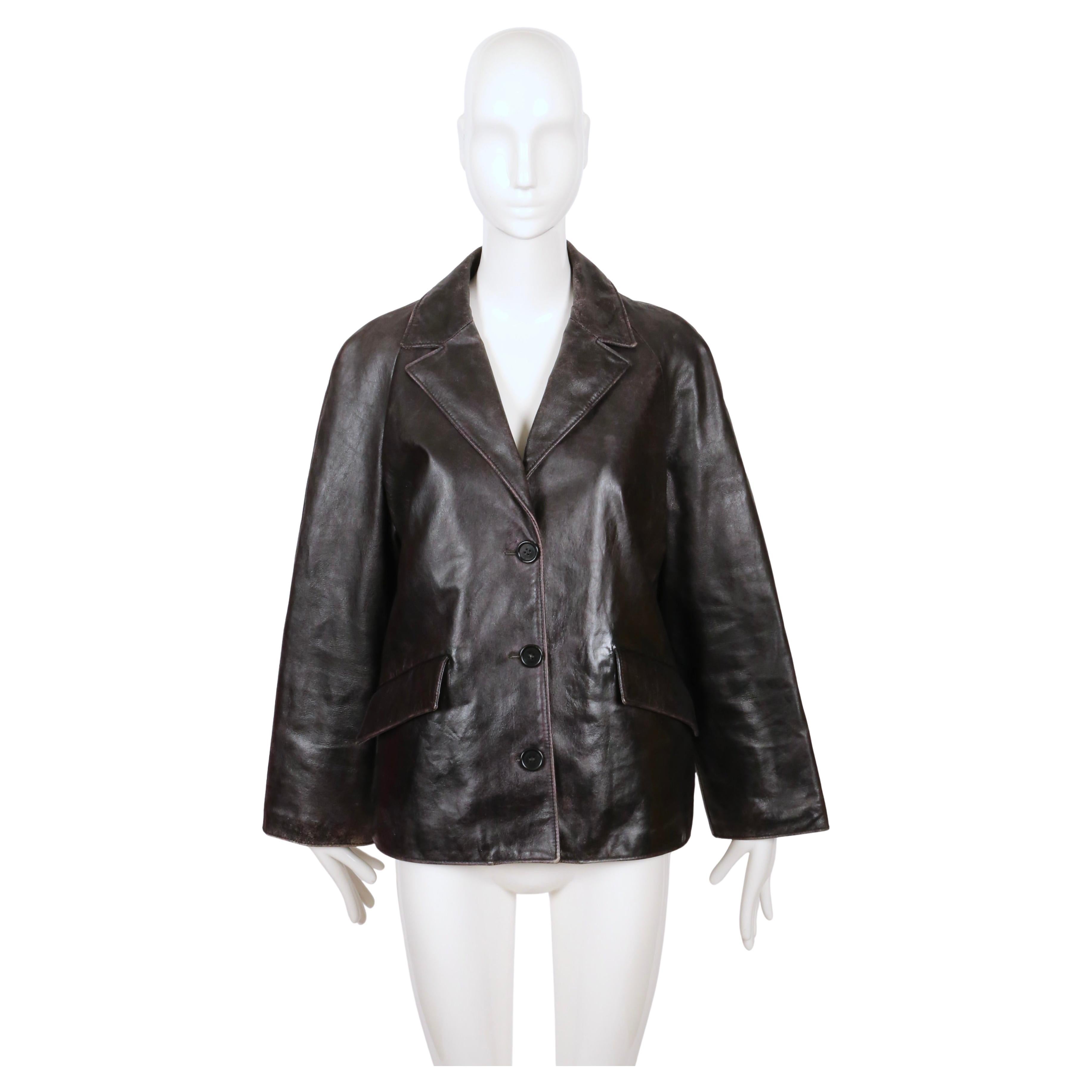 Very rare, heavily 'distressed' leather jacket with slightly cropped sleeves and back half belt designed by Miuccia Prada for Miu Miu dating to fall of 2000 as seen on the runway. Color is brown/black. Labeled an Italian size 42. Approximate