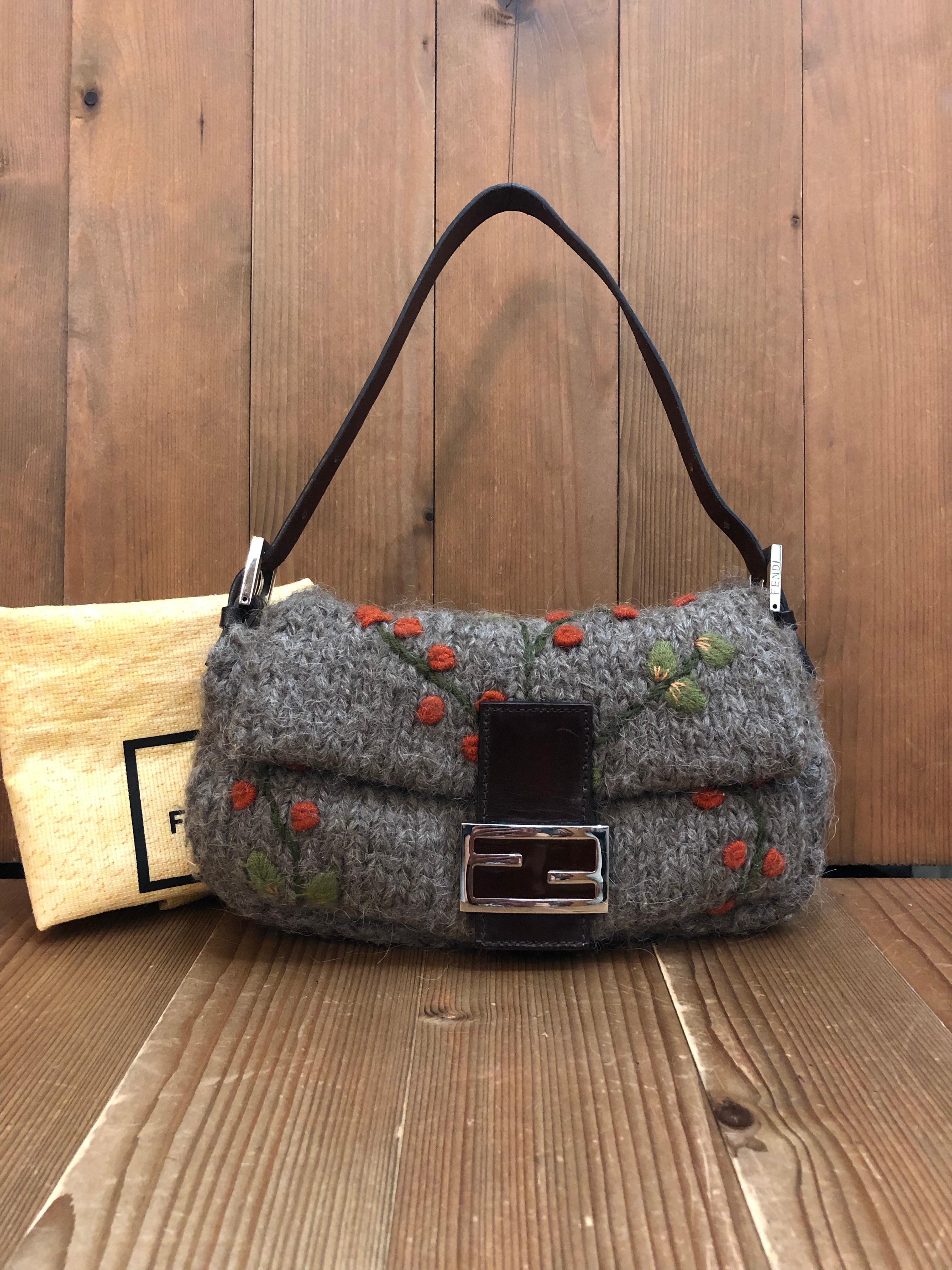 This unusual Fendi Baguette shoulder bag is crafted of grey wool embroidered with orange floral tree featuring silver toned hardware and a brown cowhide leather strap. Front leather FF flap magnetic snap closure opens to an orange satin interior