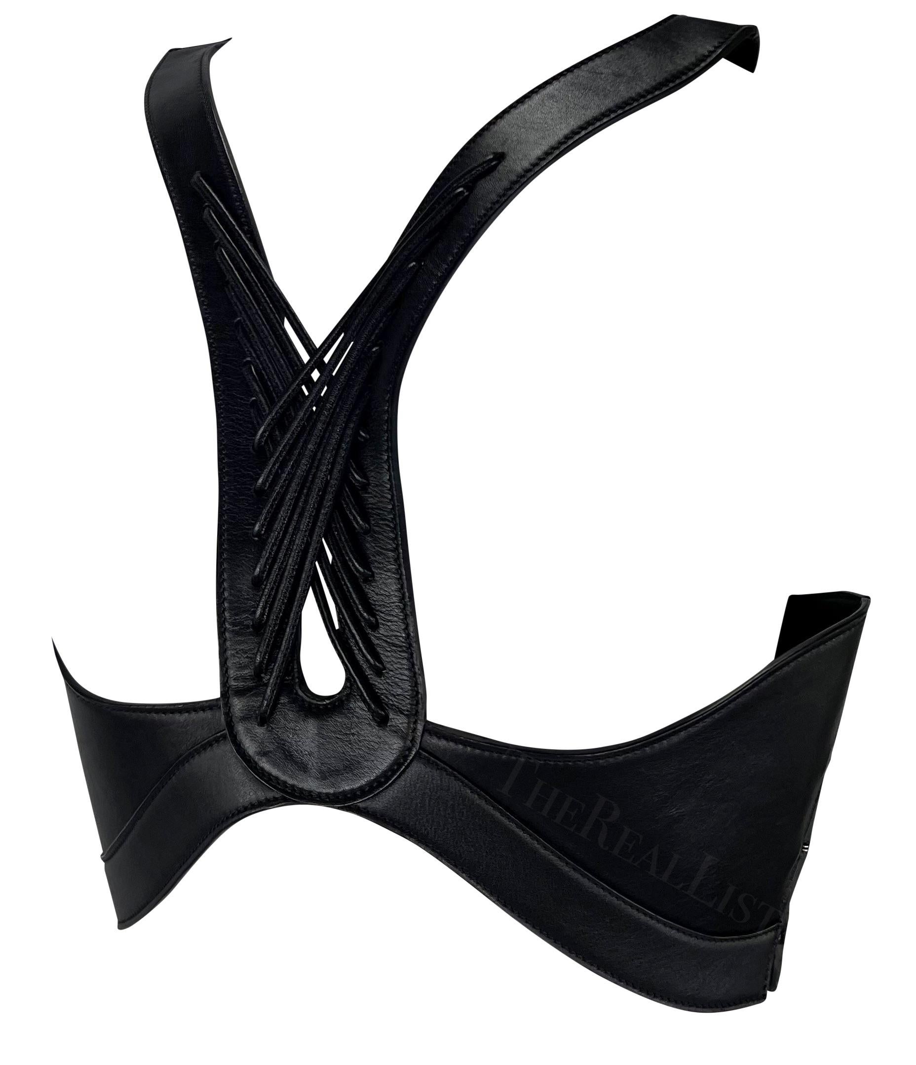 Ich präsentiere ein unglaubliches schwarzes Ledergeschirr von Alexander McQueen.
Betreten Sie das Reich der Avantgarde-Mode mit diesem fesselnden Leder-Harness-Top aus den 2000er Jahren. Dieses sorgfältig gefertigte, außergewöhnliche Stück zeigt die