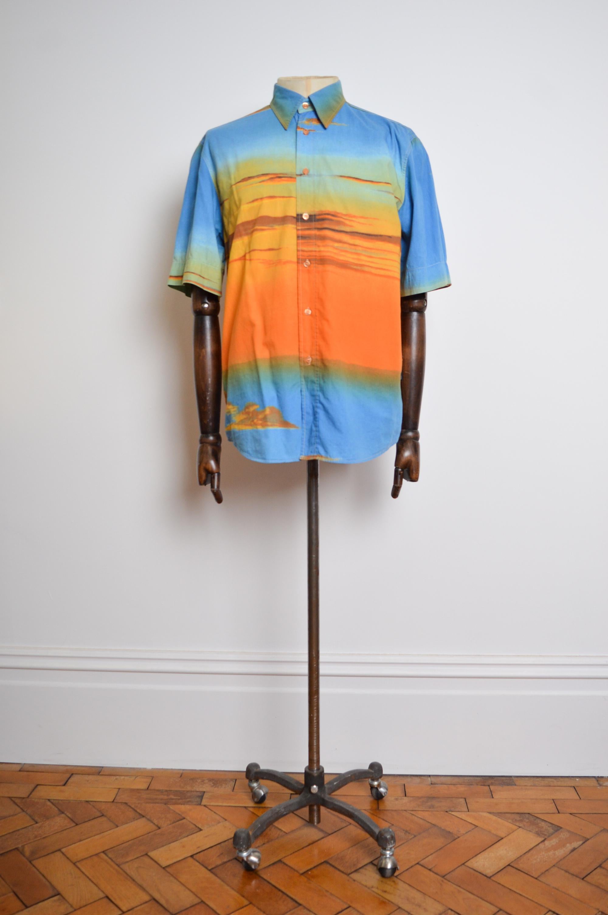 Chemise en coton imprimé coucher de soleil 'MOSCHINO' de l'époque Garage du début des années 2000, fabriquée à partir d'un tissu imprimé dans des tons ombrés bleu et orange. 

Nous avons également la veste et le pantalon assortis disponibles à