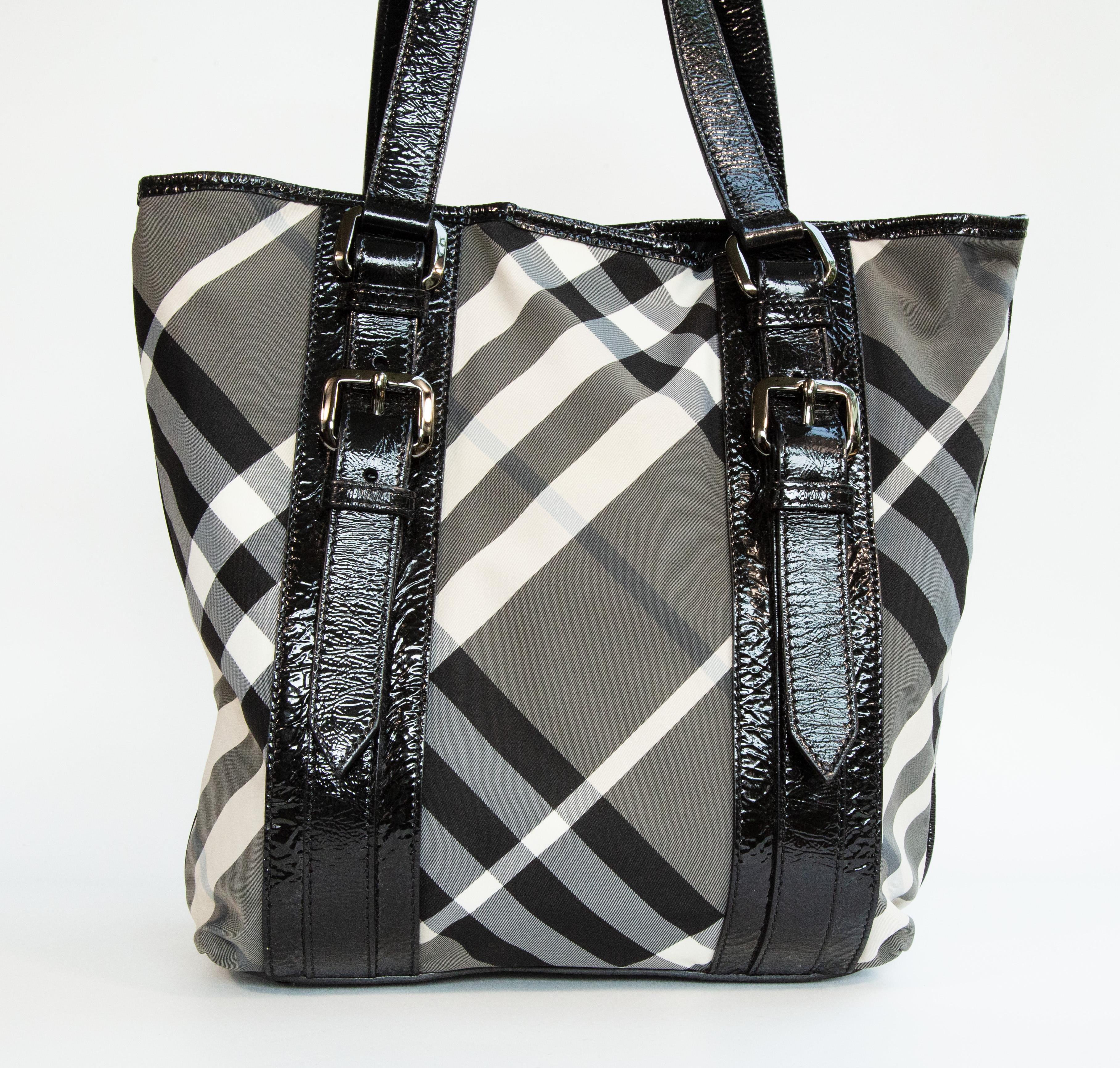 Sac fourre-tout/épaule Burberry en nylon à carreaux Nova noir/blanc/gris, garni de cuir verni noir et de ferrures couleur étain. L'intérieur est doublé de tissu noir et comporte trois poches latérales, dont une avec fermeture éclair. Le sac peut