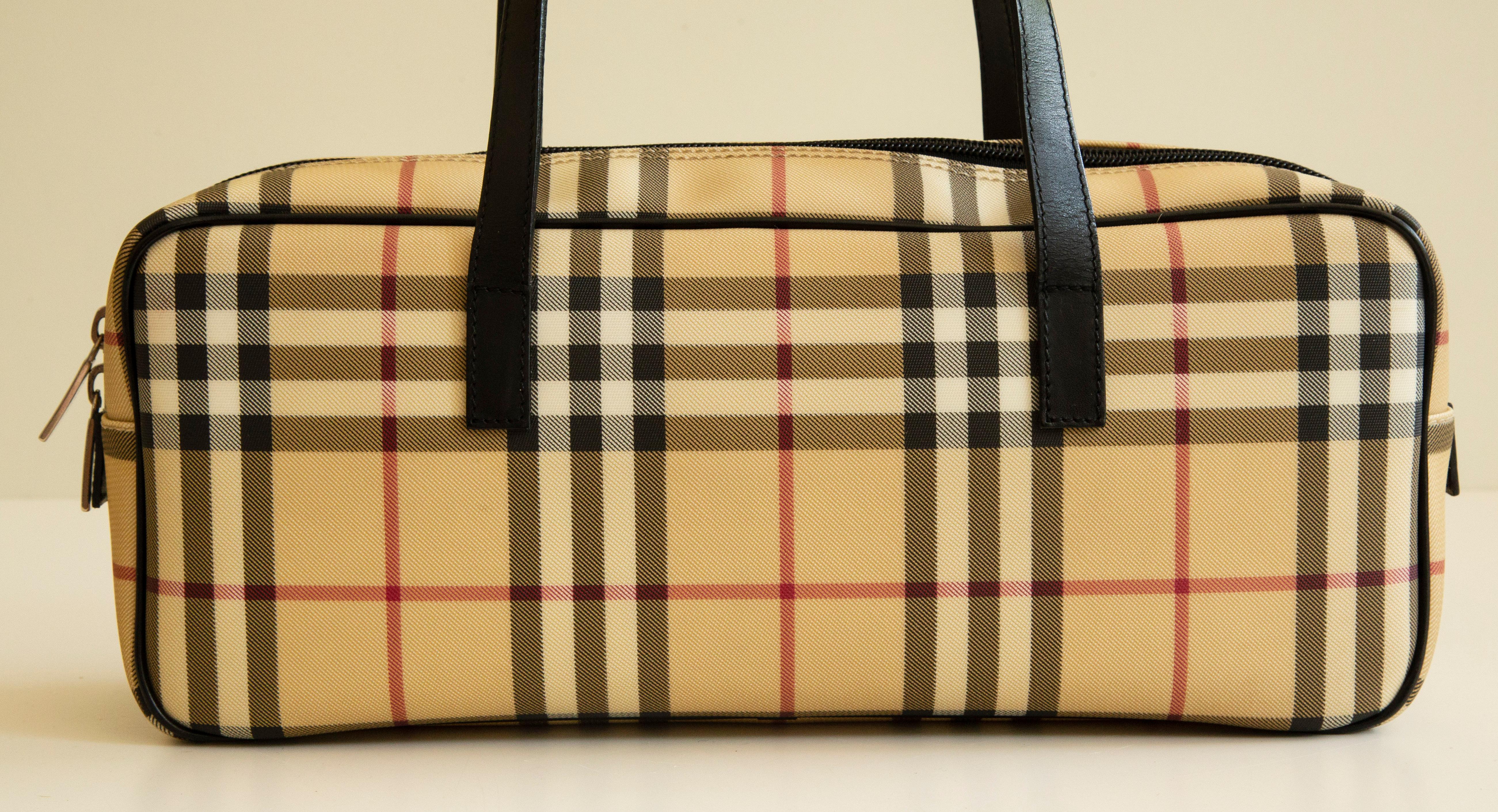 A vintage Burberry shoulder bag made of multicolor classic check pattern with black leather trim, and silver tone hardware. The interior is lined with black canvas and next to the major compartment it features one side pocket with a zipper. The