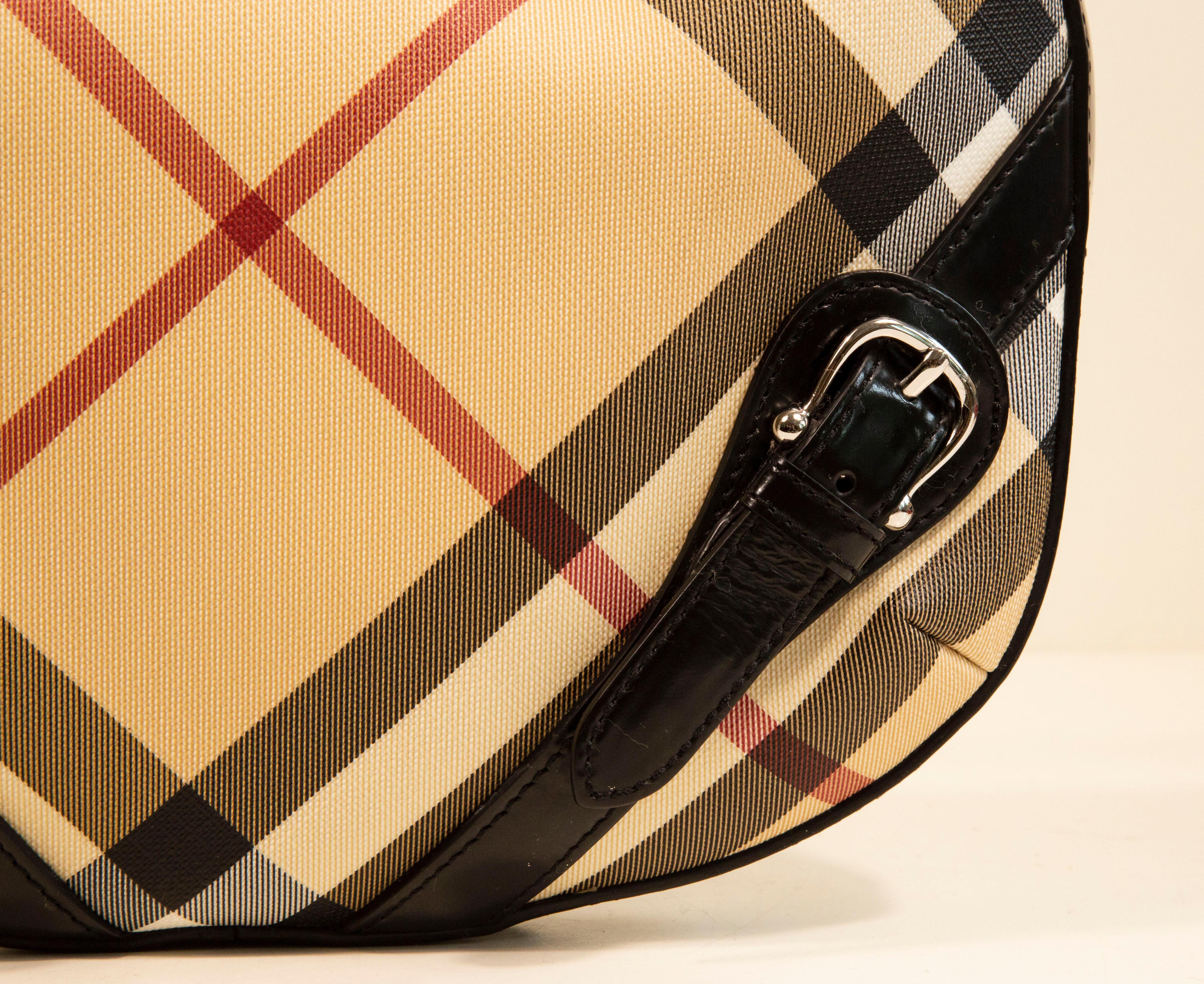 Burberry shoulder bag made of vinyl coated canvas with the Nova Check print. The bag features a black leather finish, and silver toned hardware. The interior is lined with beige fabric, and next to the major compartment it features three side