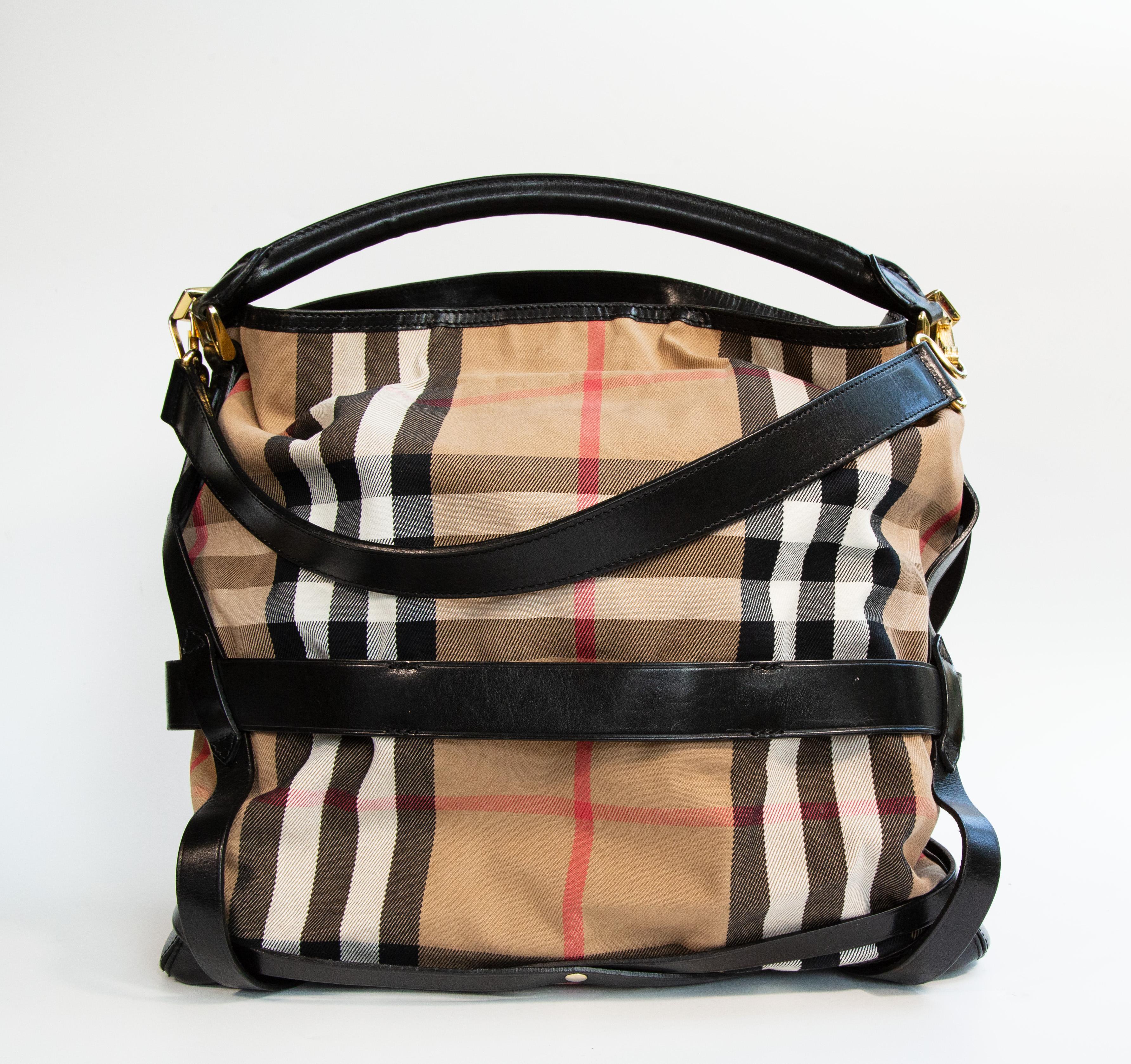 Burberry shoulder bag made of multicolor check canvas with black leather finish and gold toned hardware. The interior is lined with black canvas and it consists of two major compartments and two zipped pockets of which one has two slide pockets. The