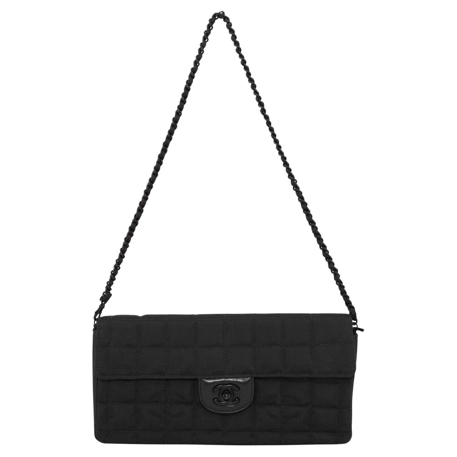 Super chic Chanel Travel East-West bag from the early 2000s. Black quilted nylon with the interlocking CC logo trademark print throughout the nylon. Black leather surrounding the twist lock with a matte black CC logo. Interior of flap is black