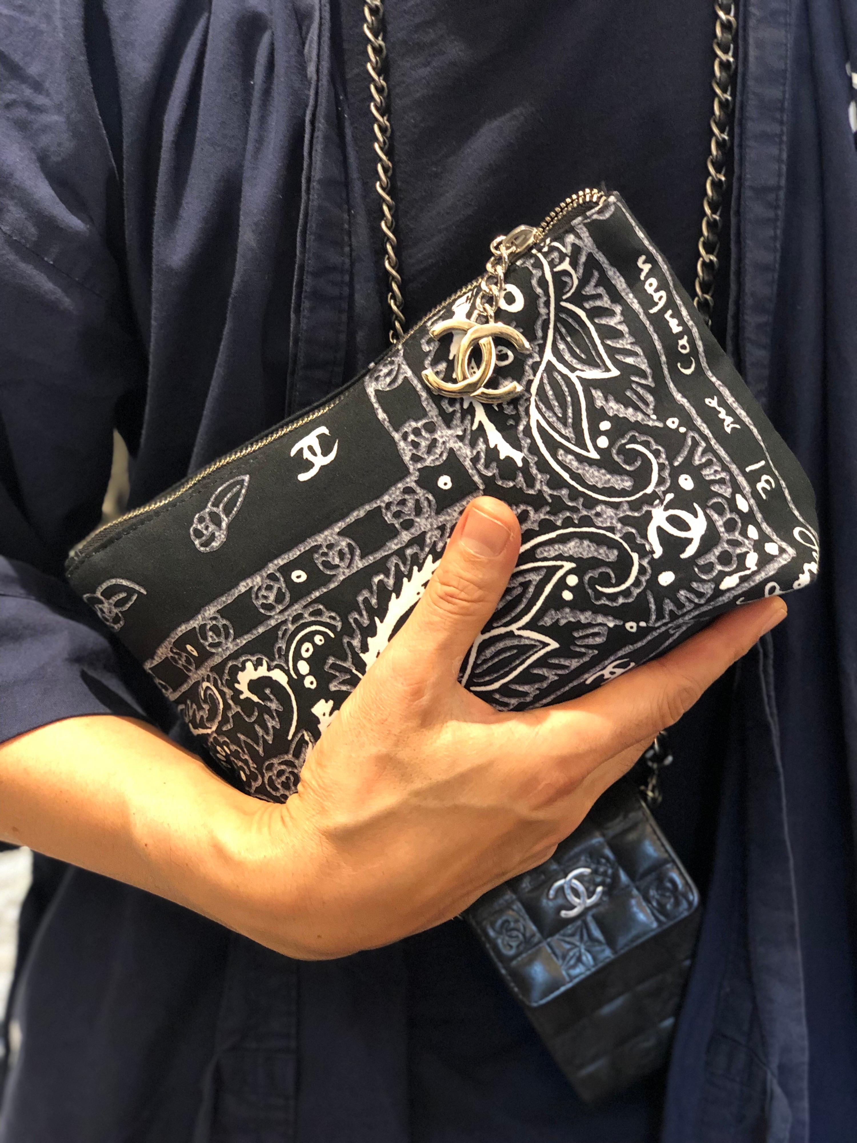 This 2000s Chanel cotton cosmetic pouch/clutch is crafted of cotton in black and white paisley prints featuring silver toned hardware. Top zipper closure opens to a black terry cloth interior featuring patch pocket. A small ring is added to the end