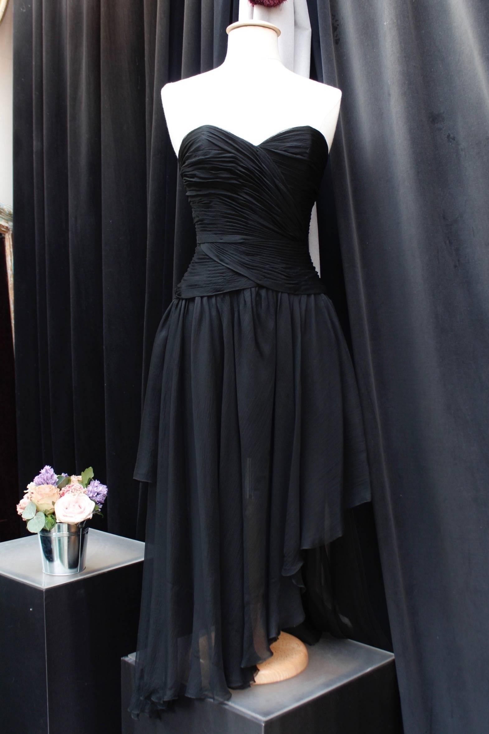 CHANEL (Made in France) Elegant evening bustier dress made of black silk chiffon featuring an asymmetrical  cut. The heart-shaped collar bustier is decorated with pleats. The skirt part is comprised of several muslin layers cut and assembled