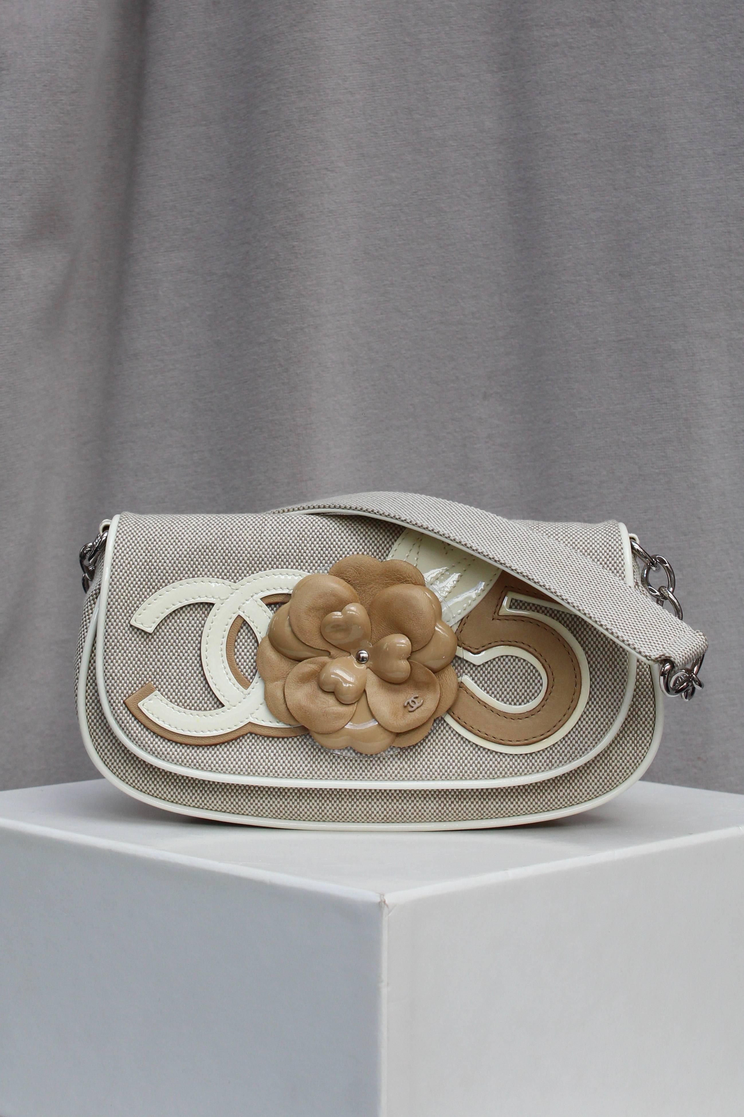 CHANEL (Made in Italy) Baguette bag made of light brown beige and white leather and canvas. It is decorated with a CC logo, a camellia and a Number 5, the very emblems of the brand. The short handle, made of canvas and calf skin, is extended by a