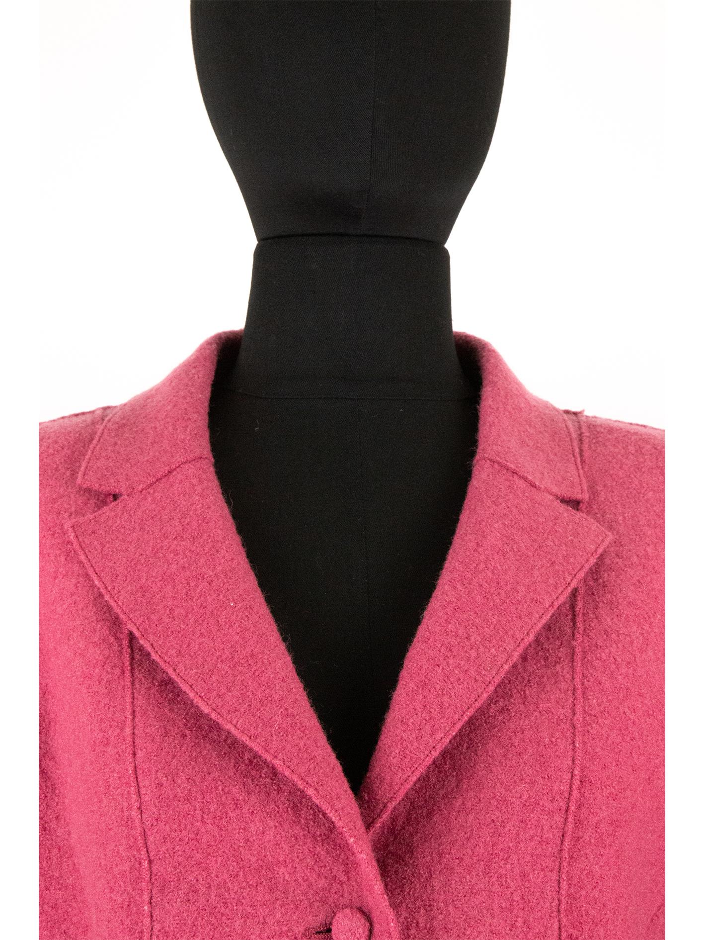 A 2000s Chanel boucle woollen jacket in a punch pink with a tailored bodice composed of curved exposed dart seams, creating a flattering silhouette on the body. The bodice includes a notched lapel collar, pockets and is fastened with self-covered