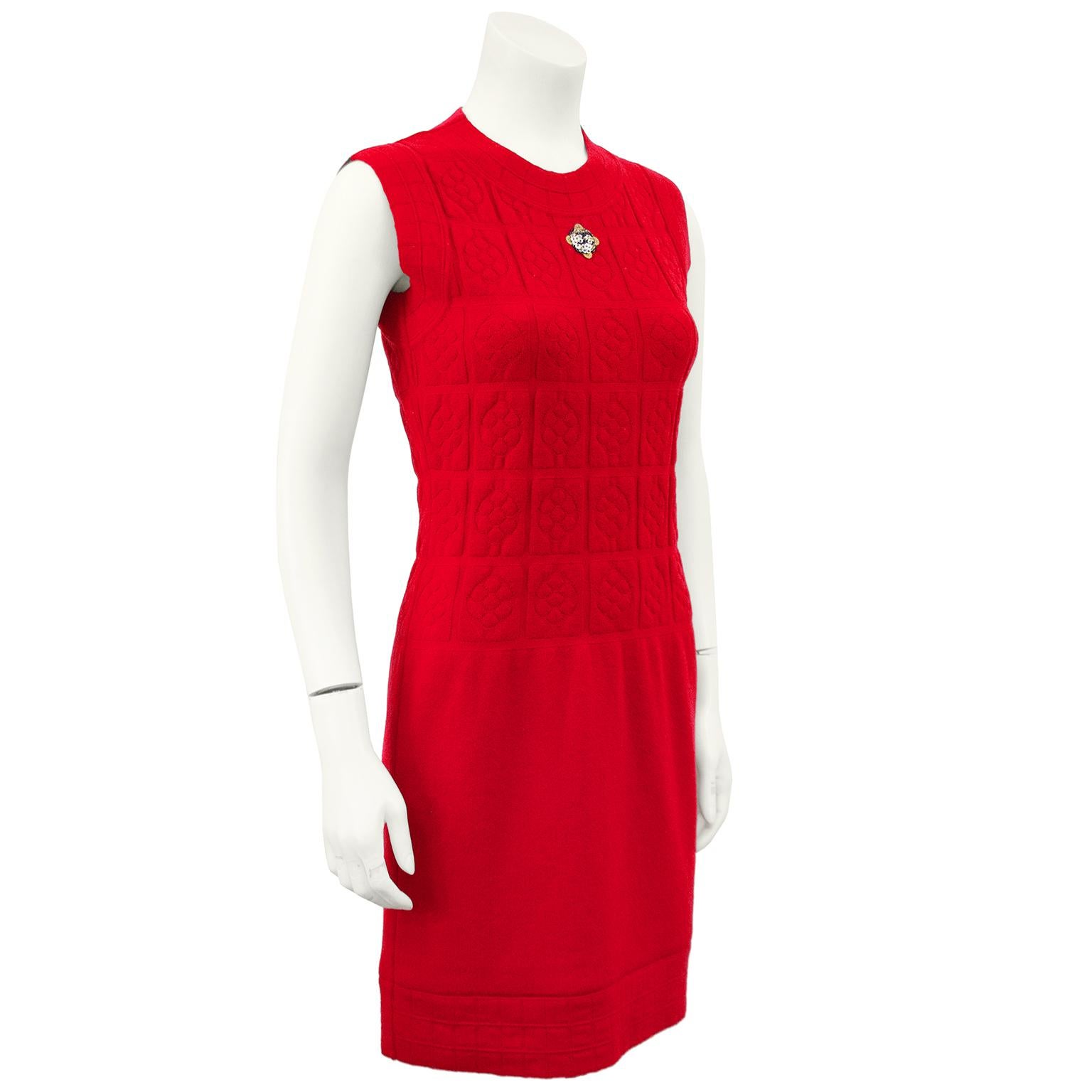 Mid 2000s Chanel red knit sleeveless dress with beaded sequin CC accent at the neck. The dress is fitted through the body with lots of give and a Camellia floral knit pattern. The skirt section has no knit pattern and falls from the low waist. The