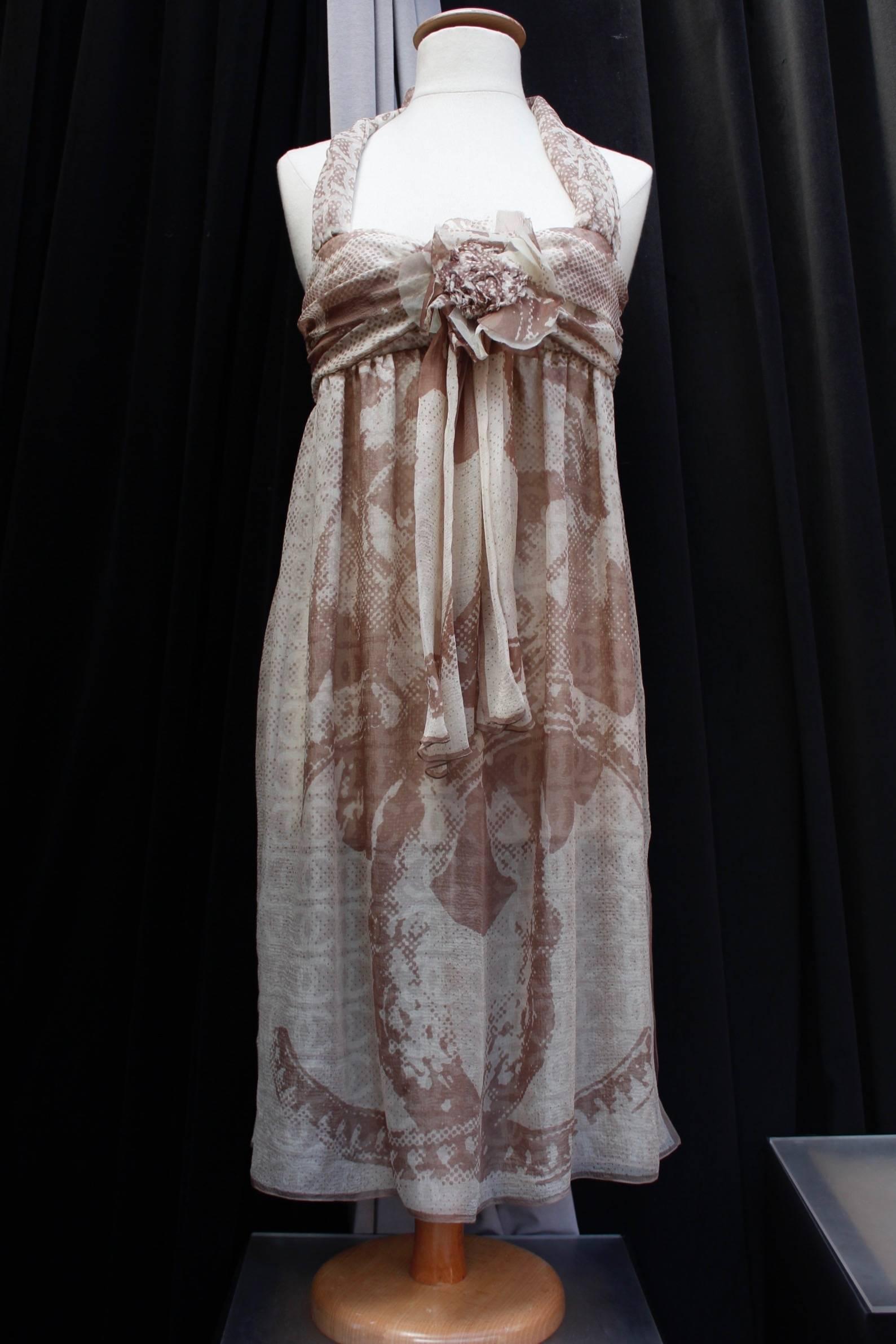 CHANEL BOUTIQUE (Made in France) Short summer dress composed of silk chiffon in light brown and beige colors. The bustier part is decorated with two fabric yokes to be tied at the back of the neck, as well as a large flower in the middle of the