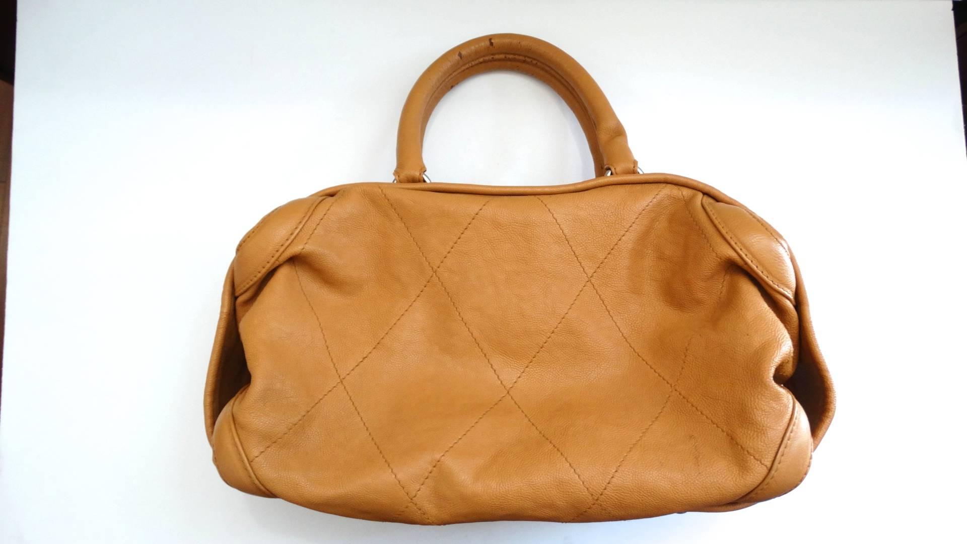The most adorable tan top handle bag from 2000s Chanel! Made of a soft tan leather with detailed quilted stitching. Slouchy, hobo style silhouette with top handle construction. Silver metal zipper across the top with large Chanel CC medallion zipper