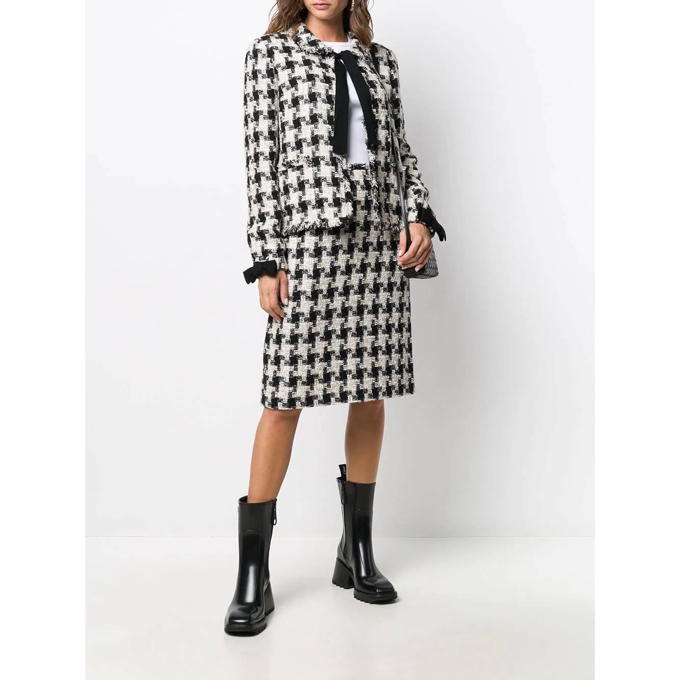 Chanel ivory and black checked tweed suit composed by jacket and skirt. Classic collar and bow fastening jacket, long sleeves and elastic cuffs with decorative black bow. Midi skirt with fringed hem and back closure with invisible zip.

Years: