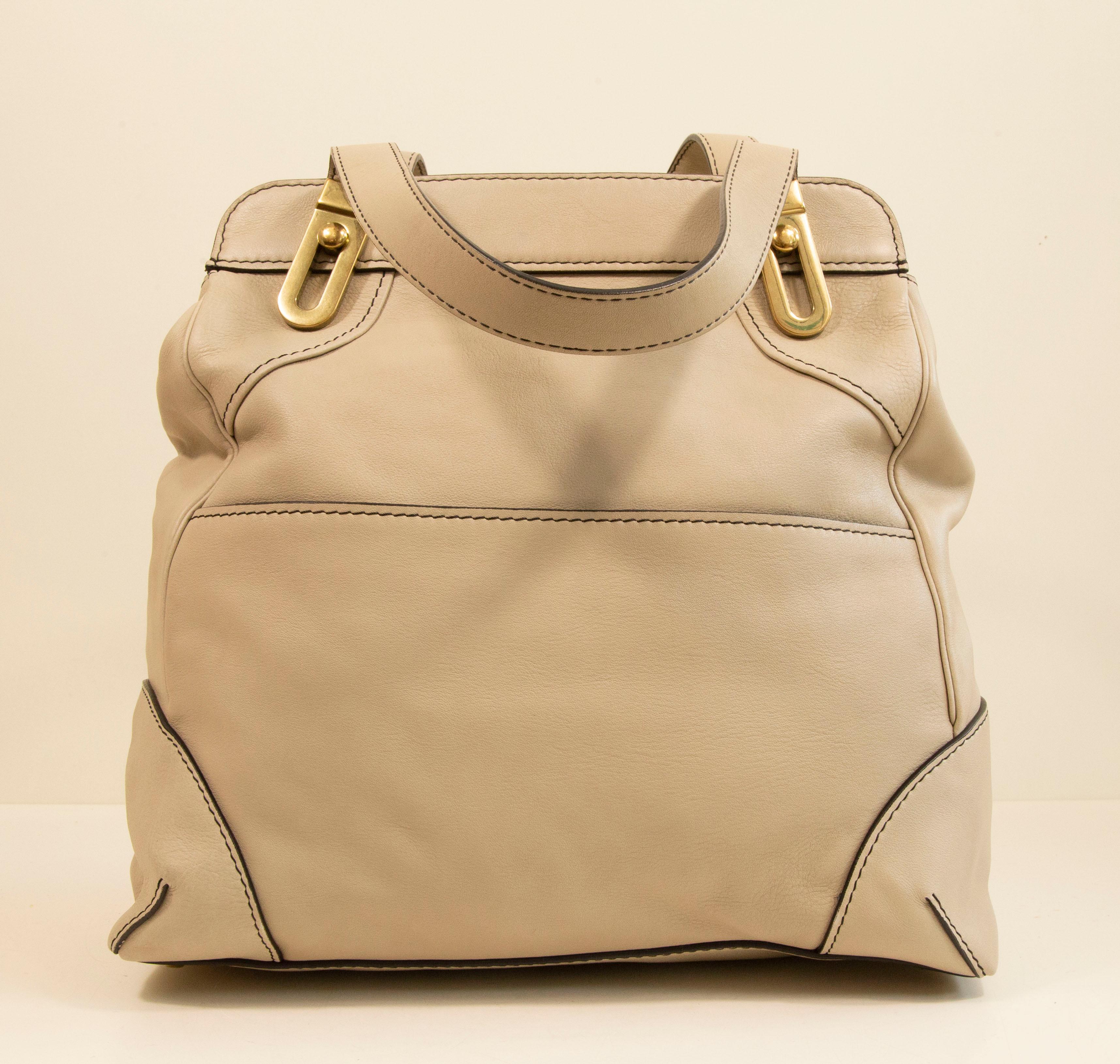 Chloe large tote bag made of beige leather with gold toned hardware. The interior is lined with black fabric and next to the major compartment it features two slide side pockets. The bag can be closed with a zipper. The bag has hardly any signs of