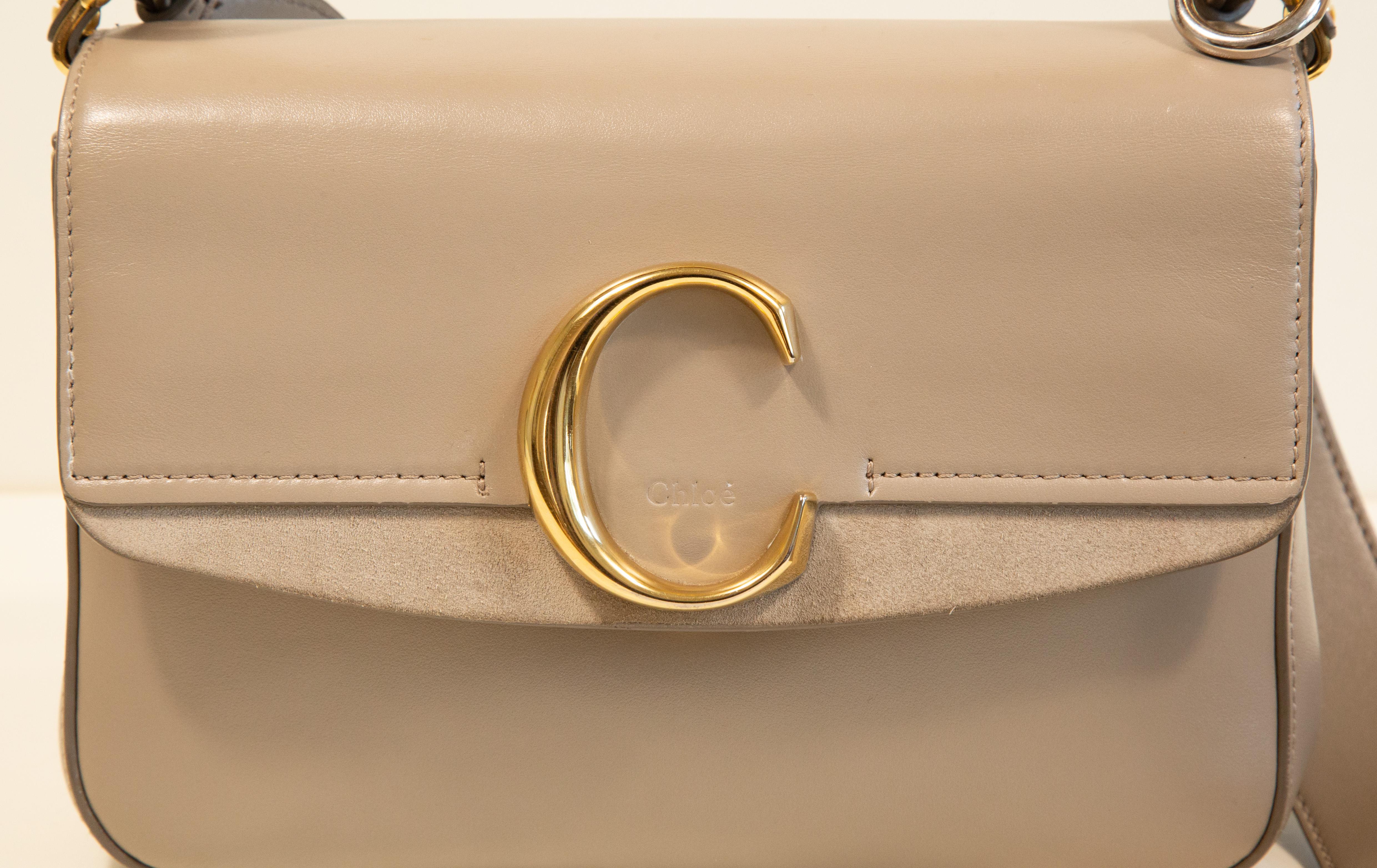 Chloe C bag made of beige leather and gold toned hardware. Next to the long shoulder strap, the bag features a short strap/top handle made of brown leather. The interior is lined with beige fabric and in addition to the main compartment it has a