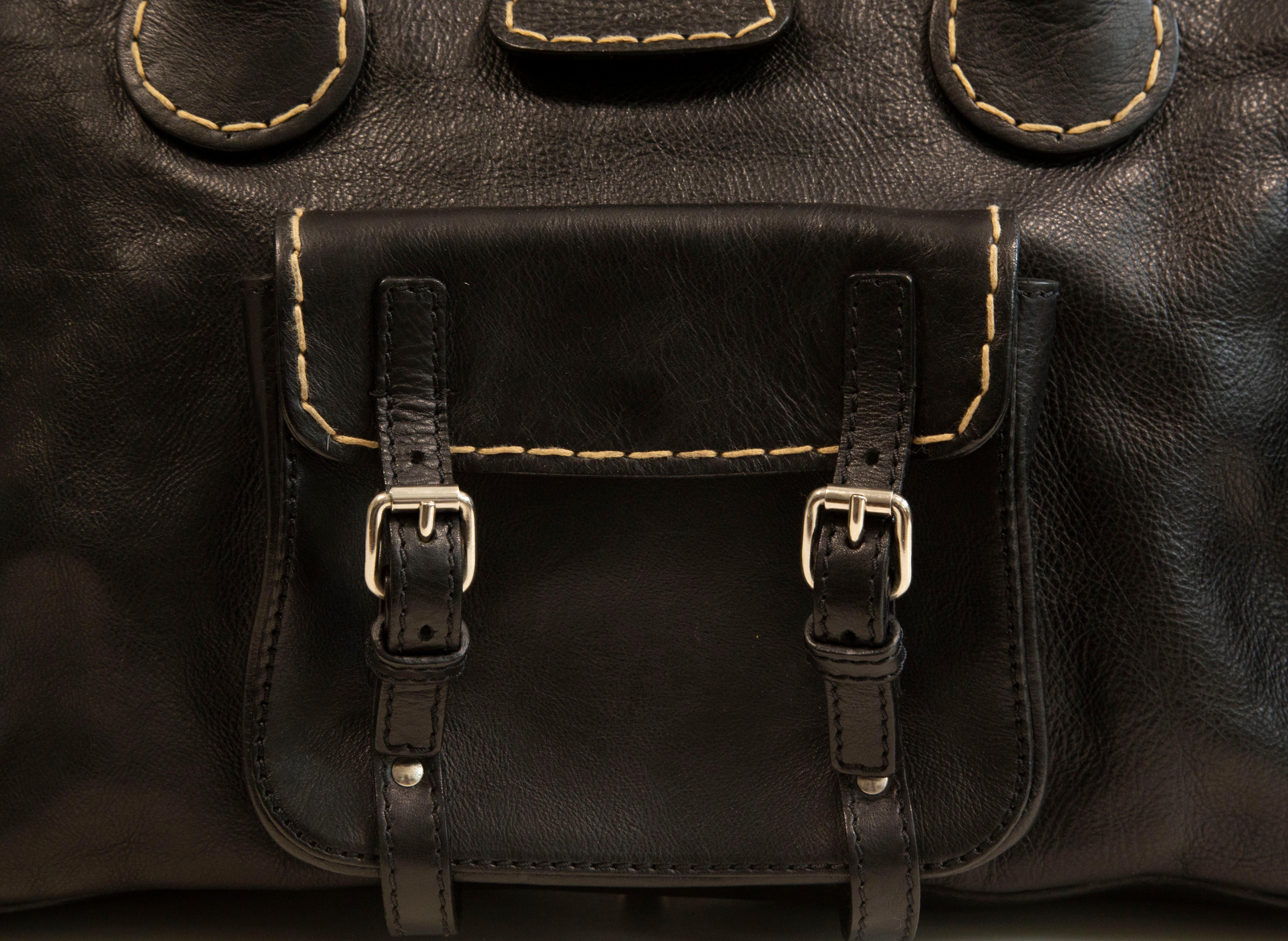 Chloe Edith top handle bag made of black leather with silver toned hardware and finished with white stitching. The bag was designed by Phoebe Philo for Chloe in 2006. The front side of the bag features a pocket in the middle. The interior is lined