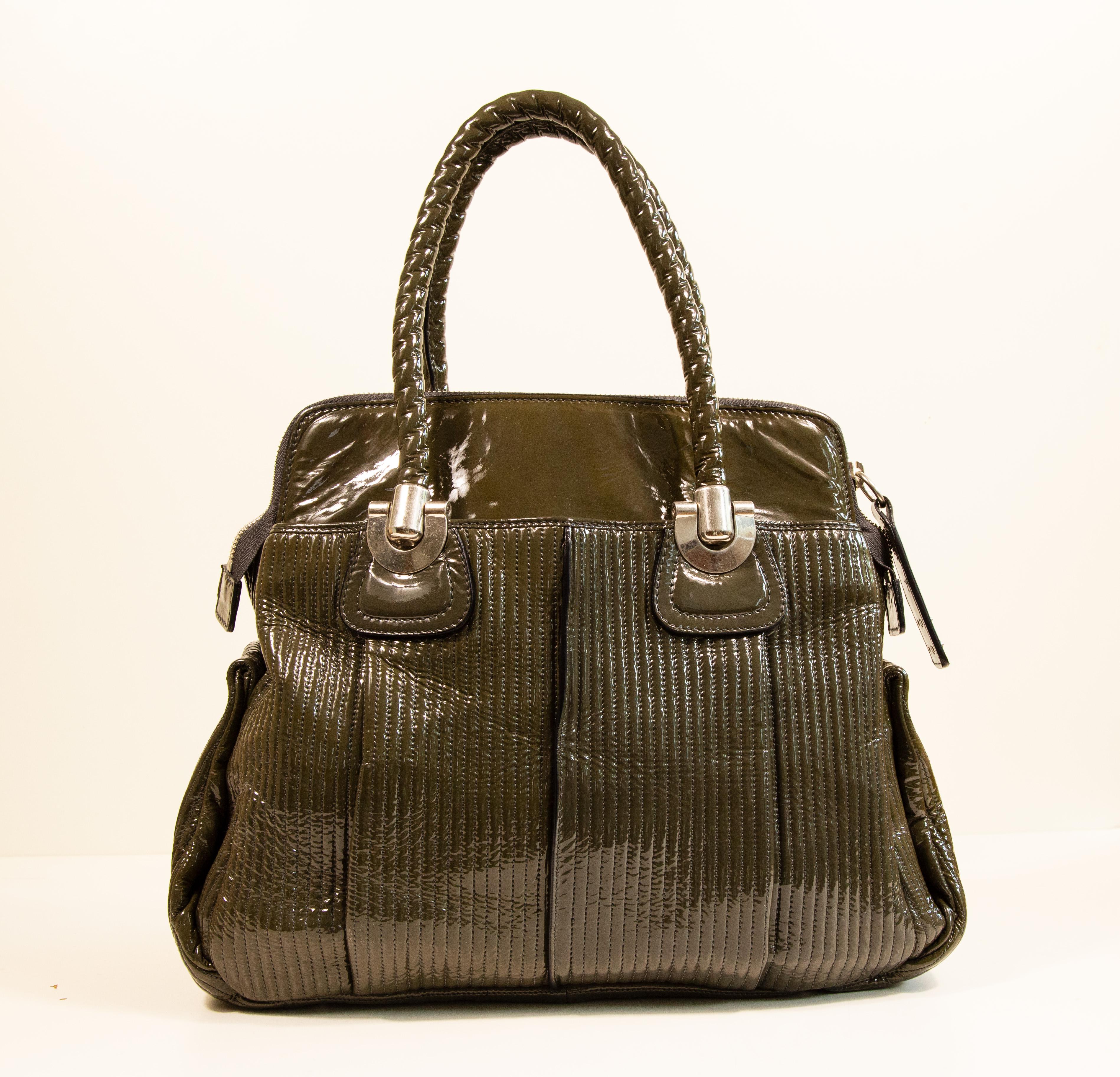 Chloe Heloise shoulder bag made of green patent leather with silver toned hardware. The interior is lined with black fabric and next to the major compartment it features two side pockets of which one has a zipper. The bag has very minor signs of use